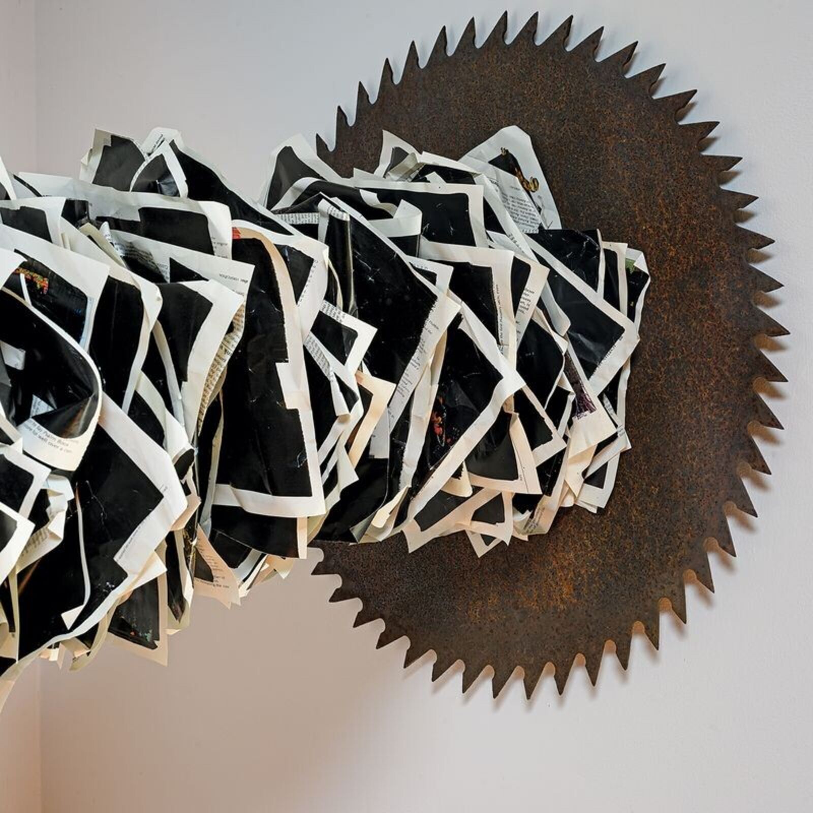 A sculptural installation featuring a jagged, metallic arch anchored by a dark block and ending in a spiked disc.