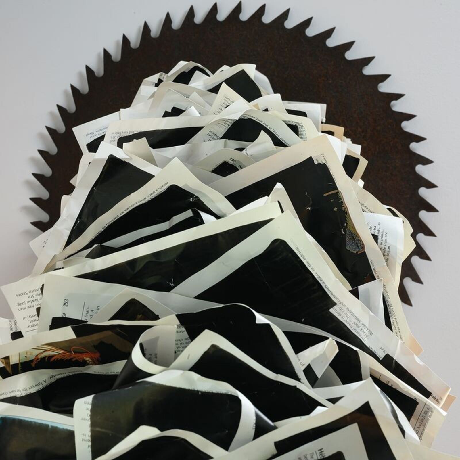 A sculptural installation featuring a jagged, metallic arch anchored by a dark block and ending in a spiked disc.