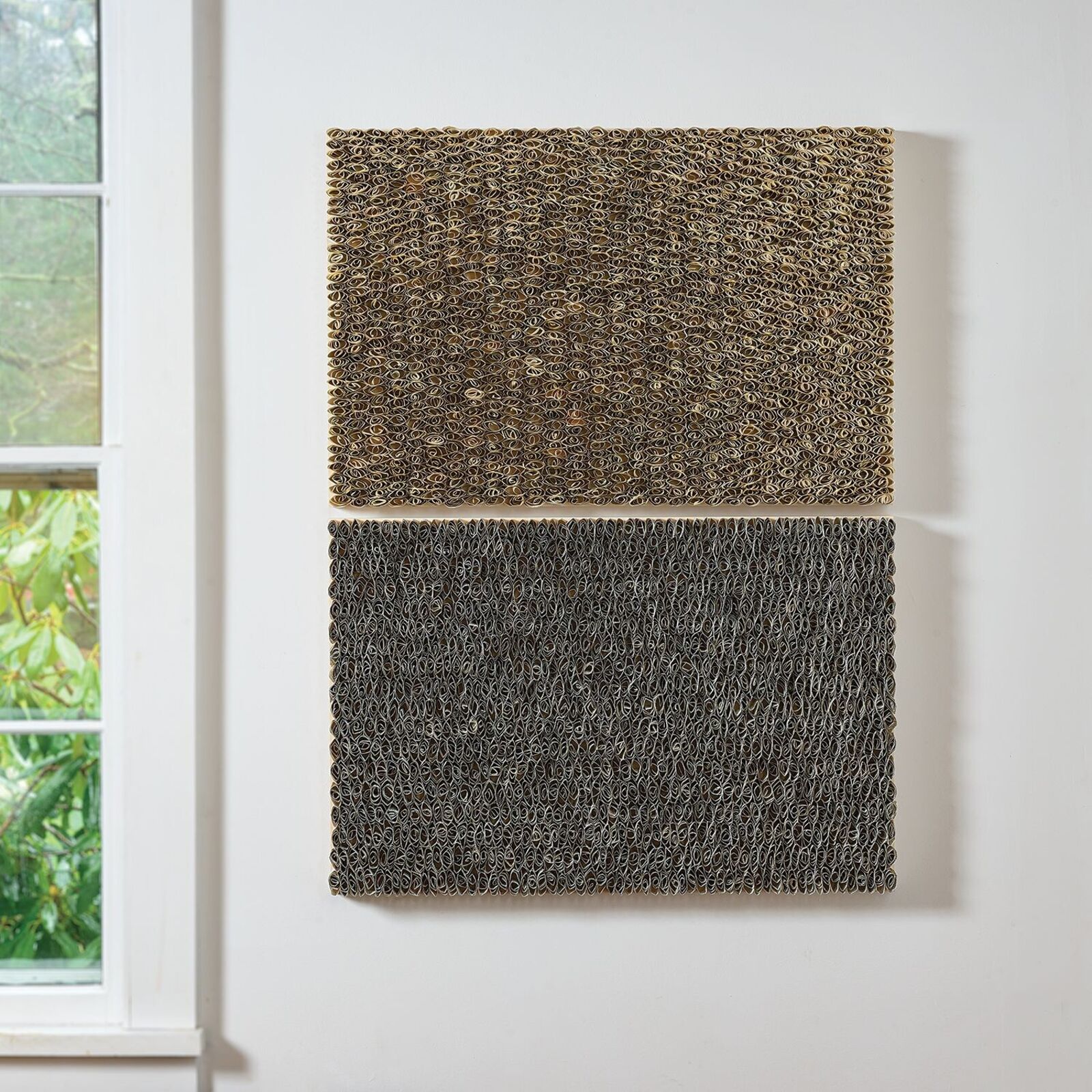 A minimalist interior wall featuring two stacked, textured rectangular panels in earthy tones.