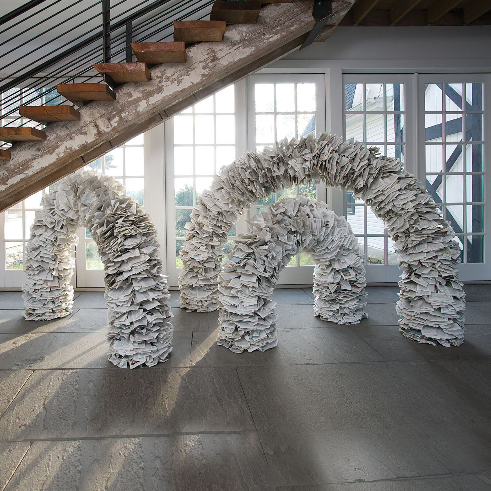 A sculptural archway constructed from thousands of layered paper pages.
