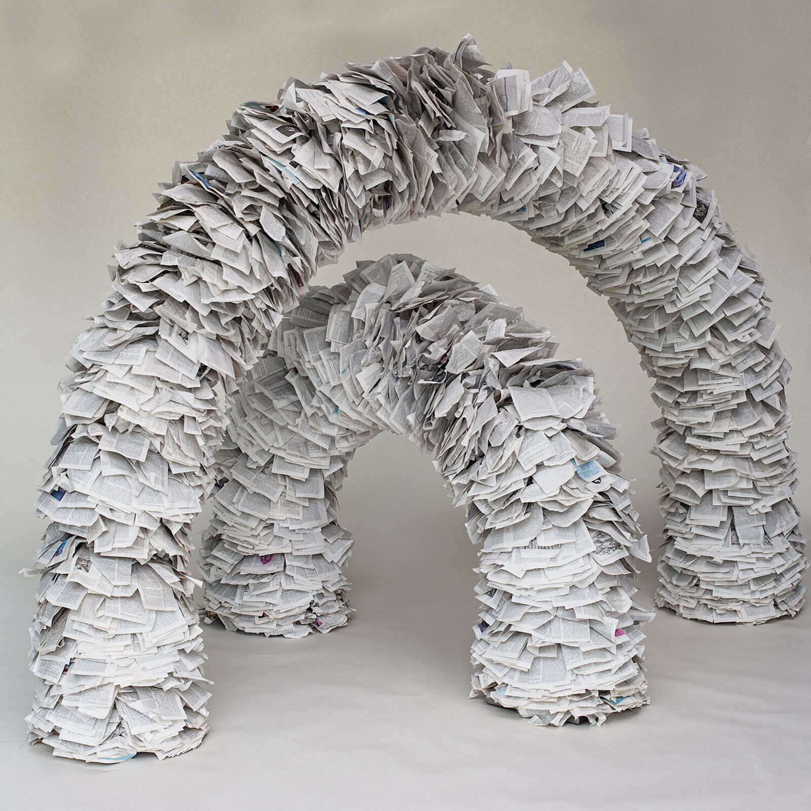 A sculptural archway constructed from thousands of layered paper pages.