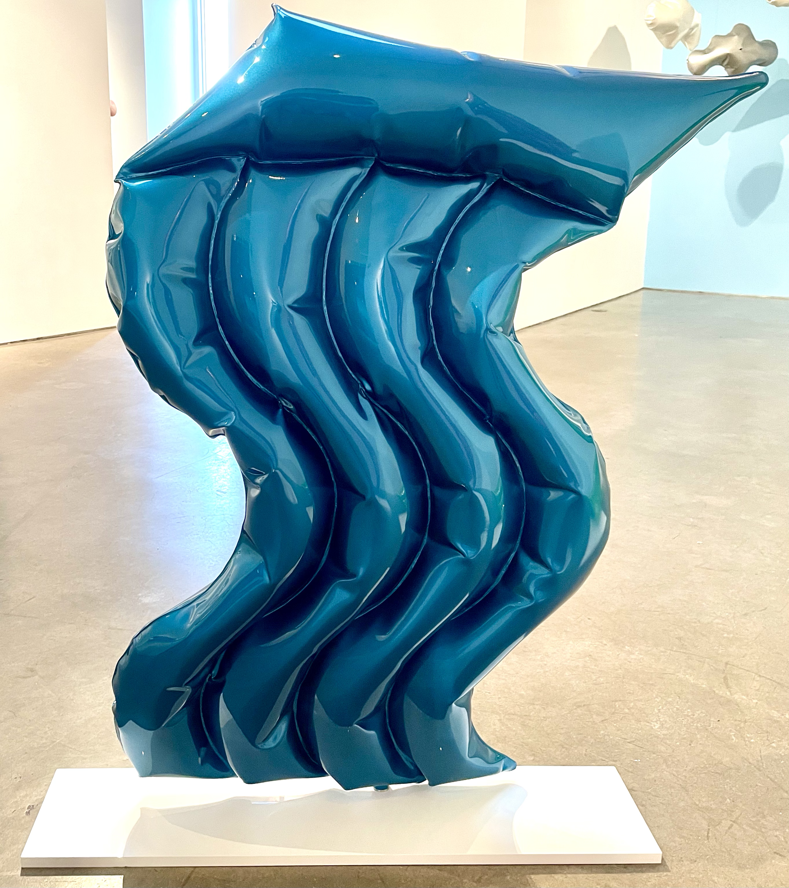 A large blue sculpture on a white pedestal in a room.