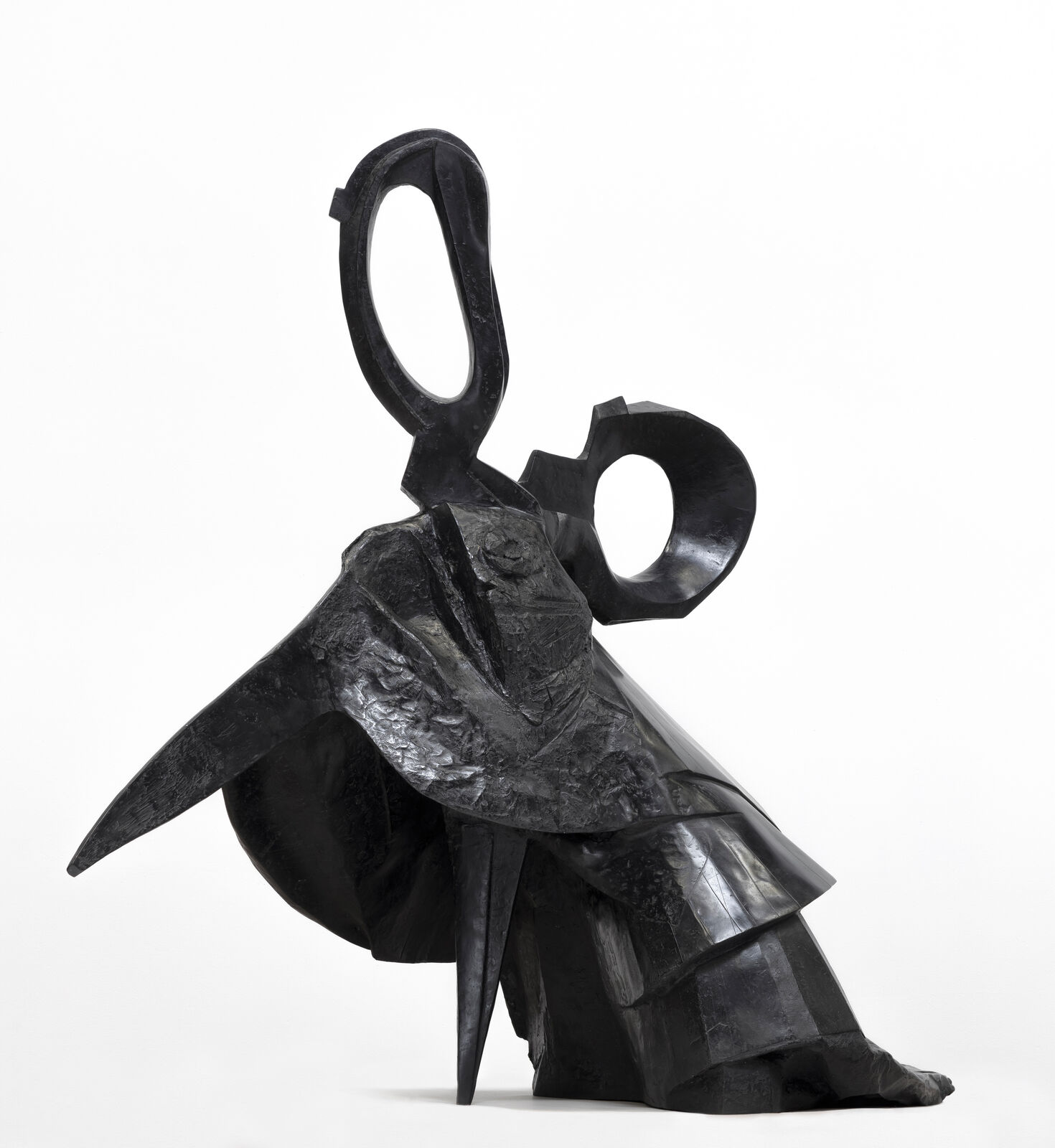 A black sculpture of a woman sitting on a chair.
