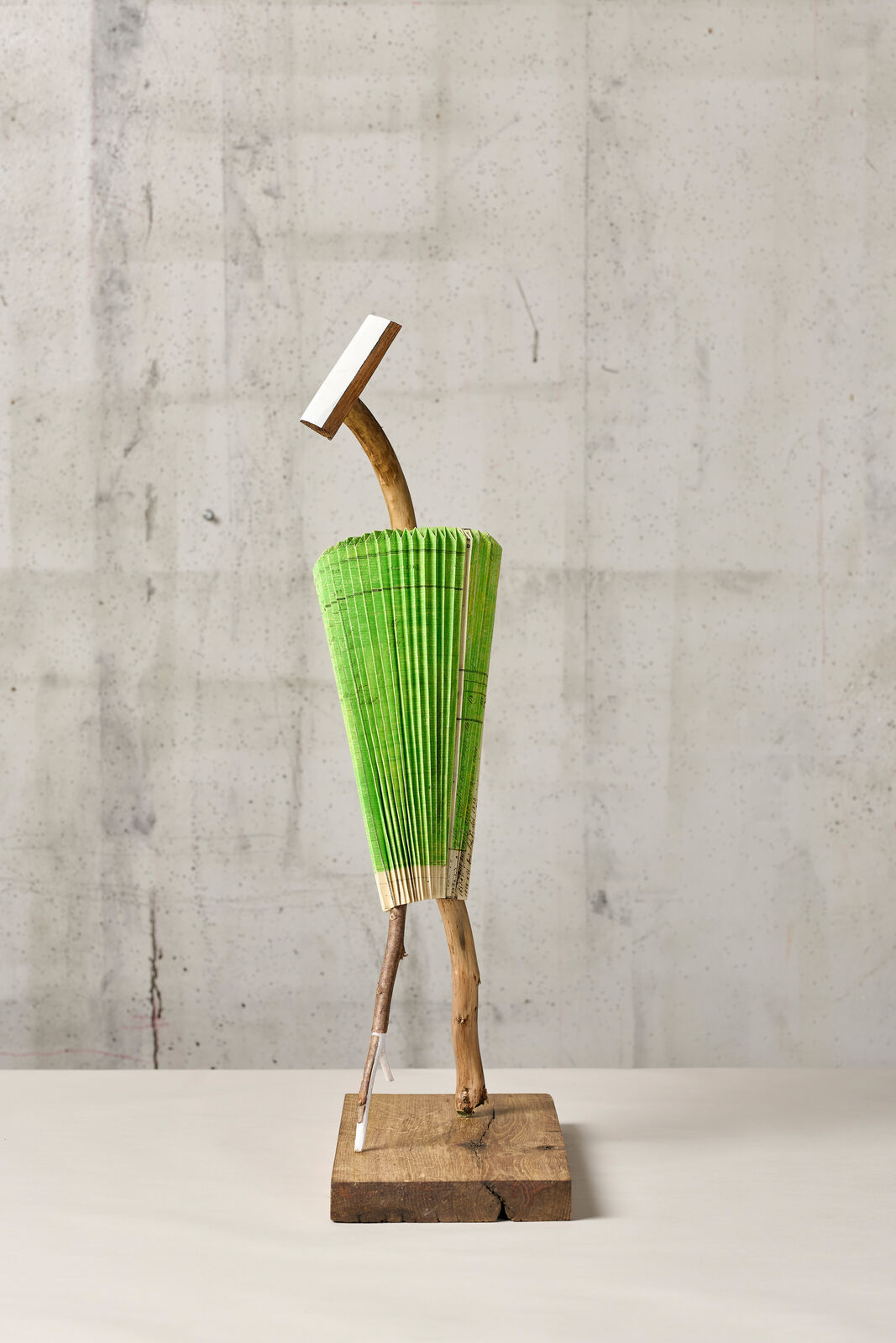 A sculpture of a man holding a green umbrella on a wooden stand.