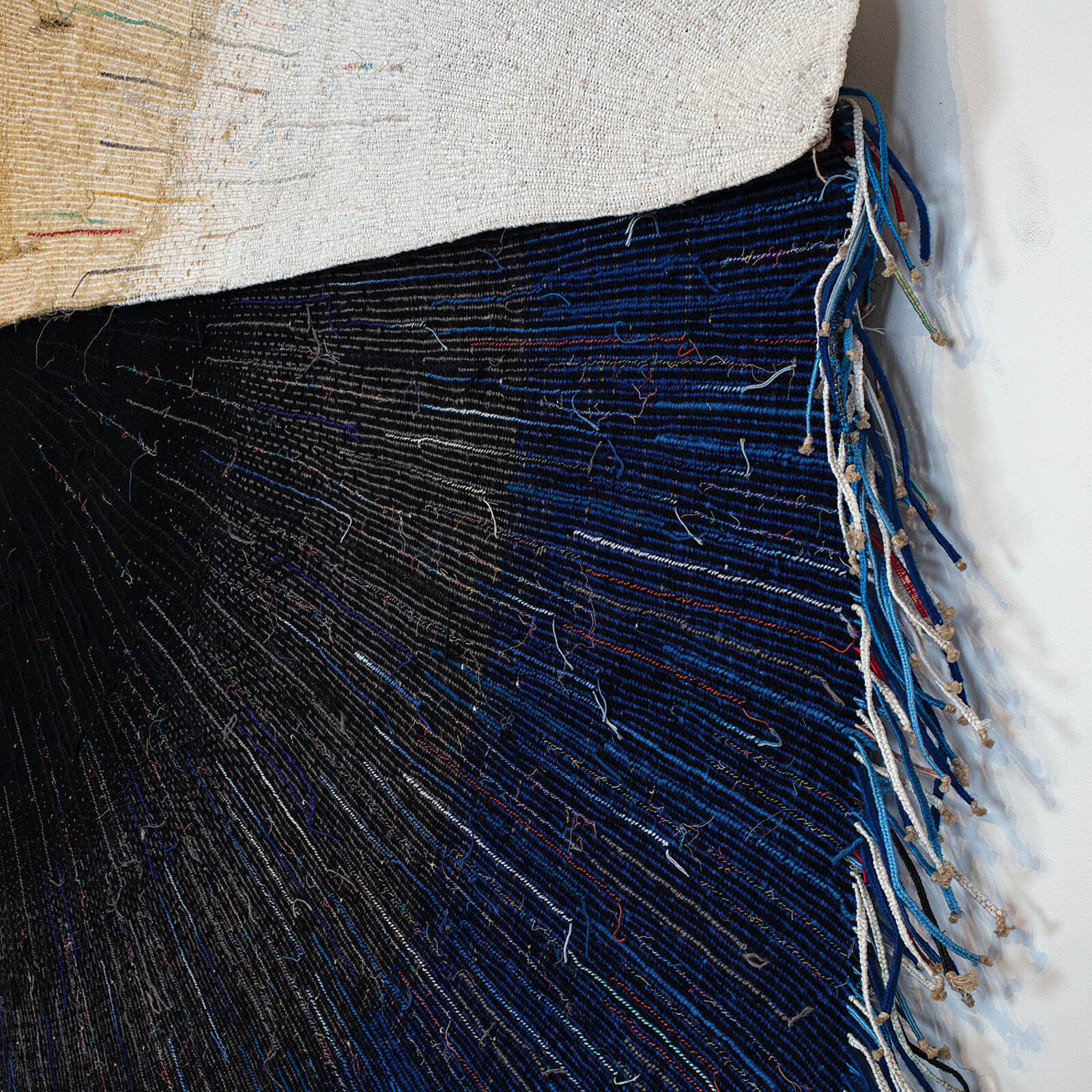 A textile artwork featuring a vertical split between earthy and deep tones, with radiating thread patterns.