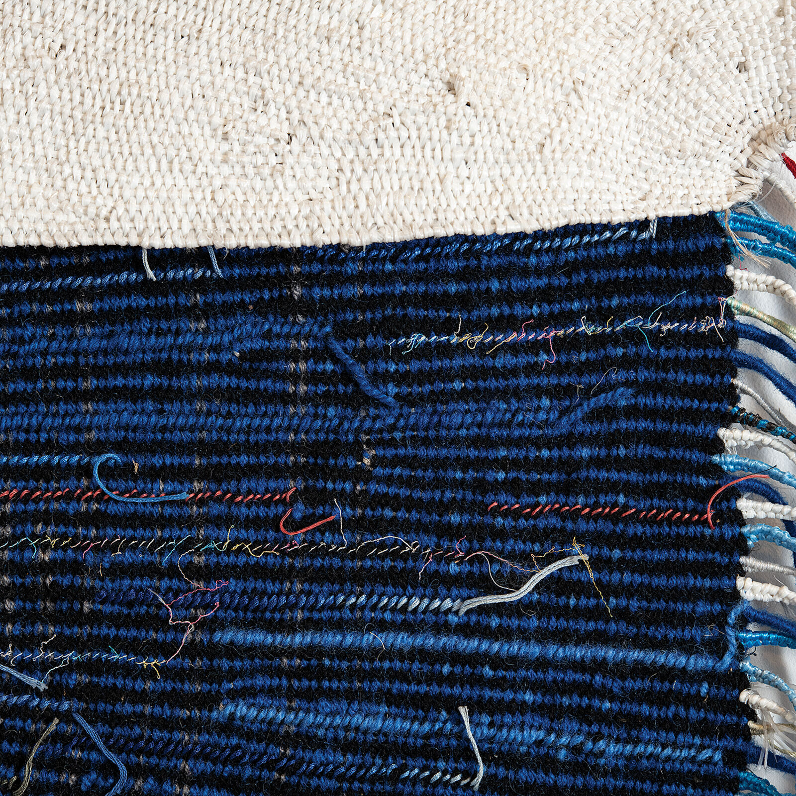 A textile artwork featuring a vertical split between earthy and deep tones, with radiating thread patterns.