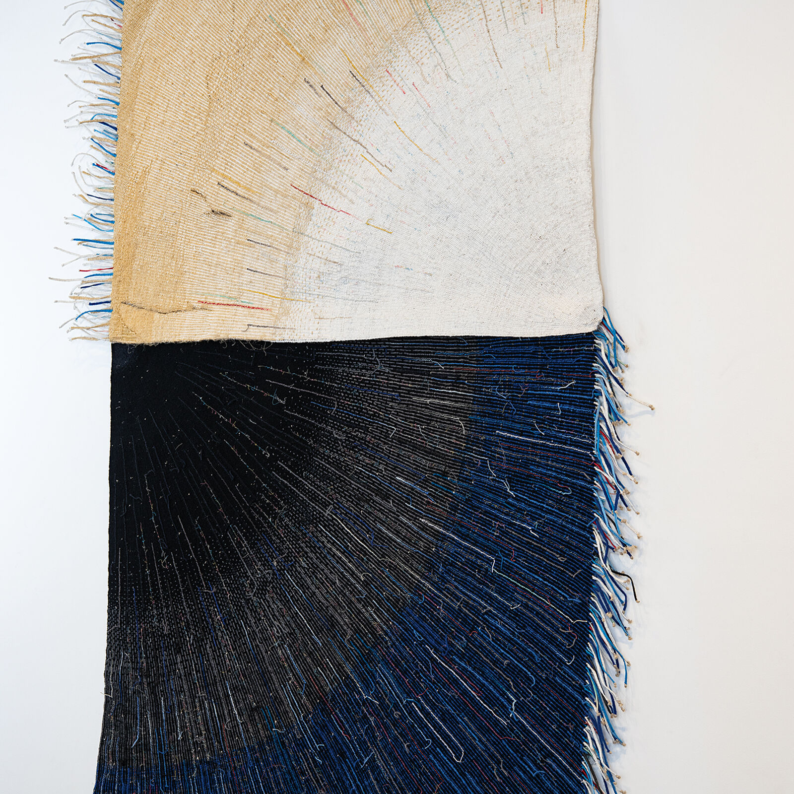 A textile artwork featuring a vertical split between earthy and deep tones, with radiating thread patterns.