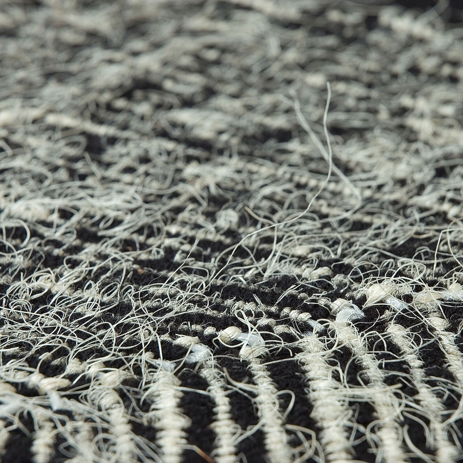 A minimalist textile artwork featuring a sunburst pattern emerging from a horizontal horizon line.