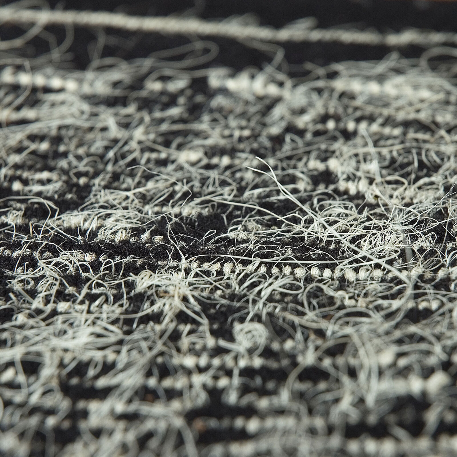 A minimalist textile artwork featuring a sunburst pattern emerging from a horizontal horizon line.