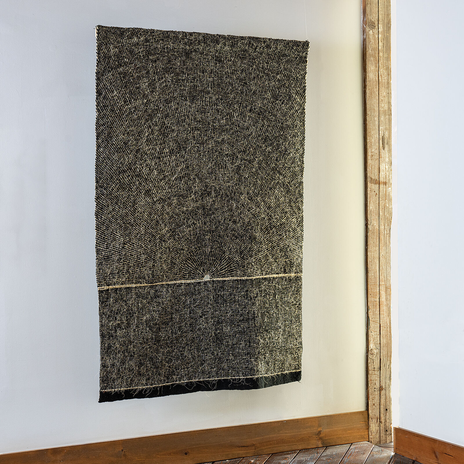 A minimalist textile artwork featuring a sunburst pattern emerging from a horizontal horizon line.