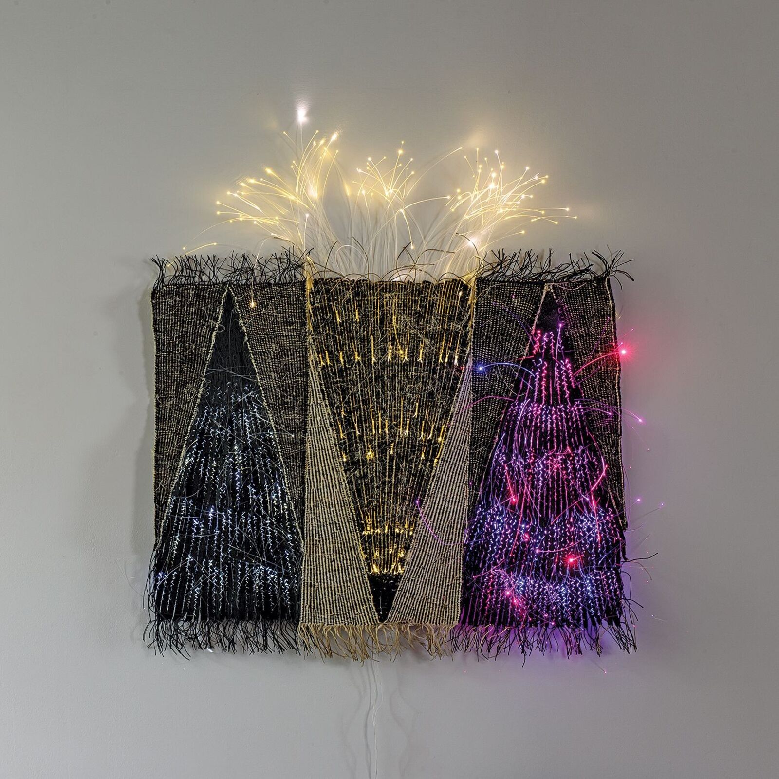A woven textile artwork featuring three triangular shapes with embedded lights.