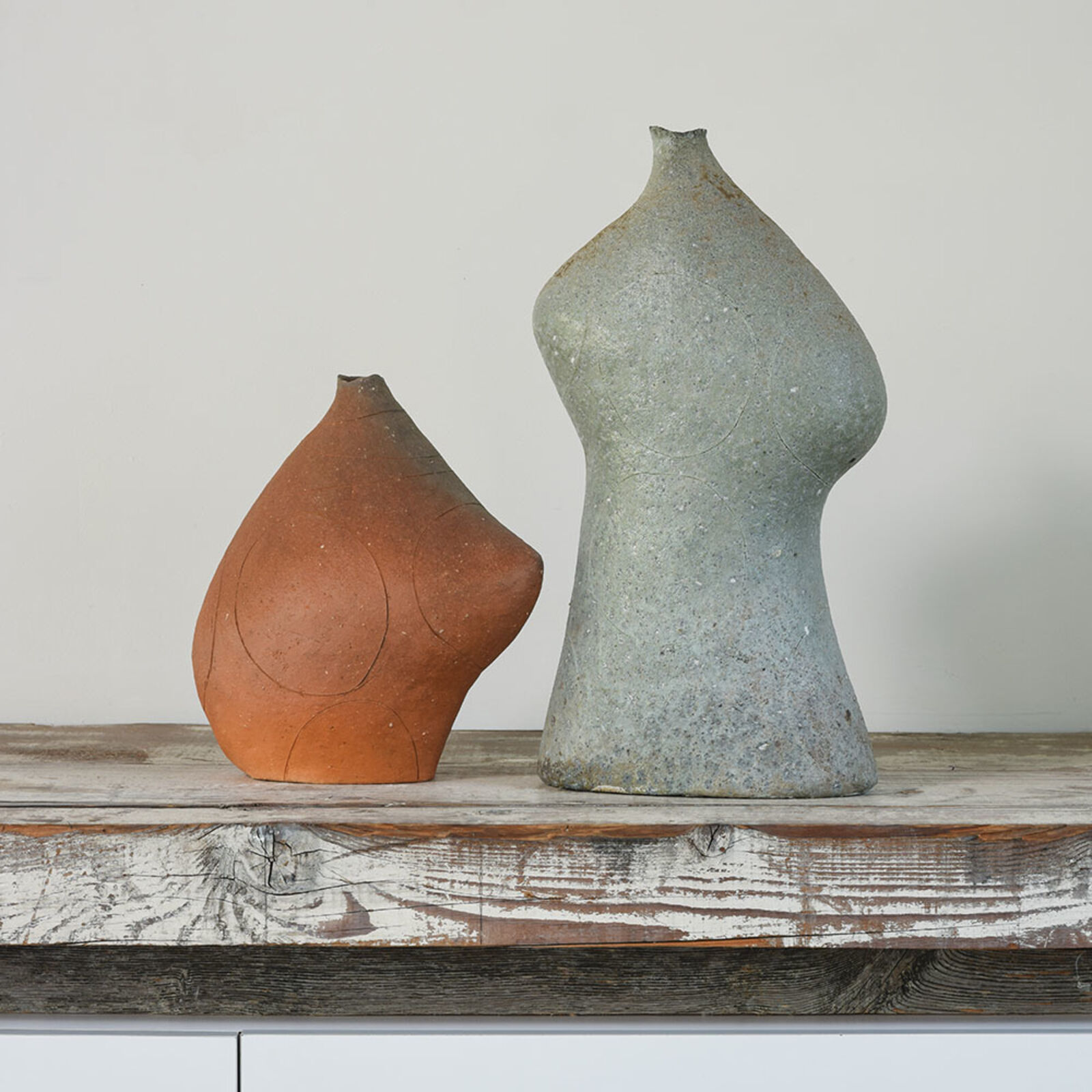 A couple of vases sitting on top of a wooden shelf.
