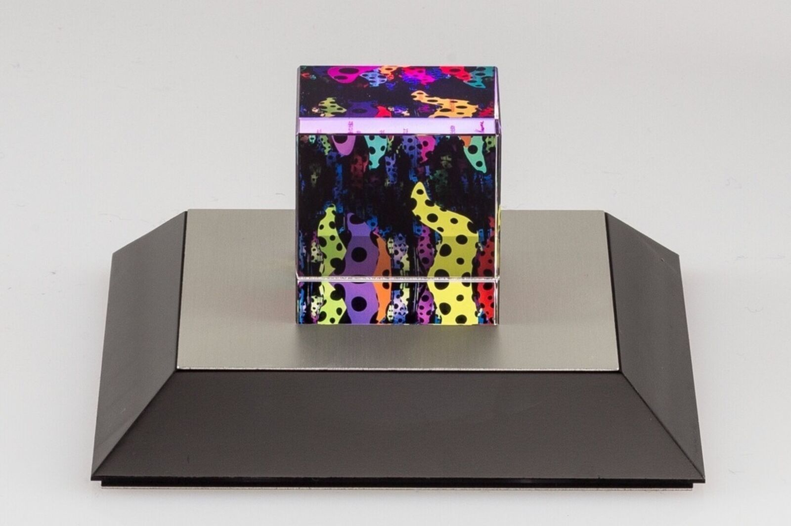 A colorful cube sitting on top of a black base.