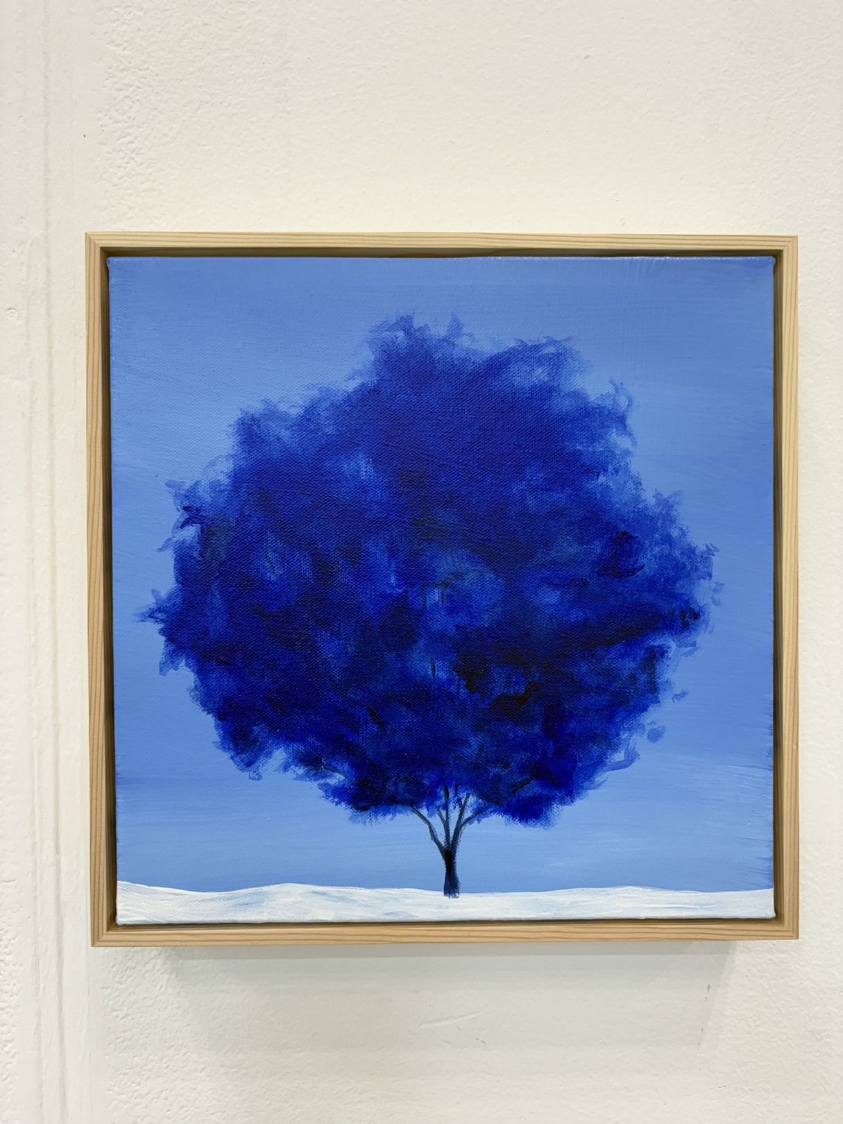 A minimalist landscape painting featuring a dark tree against a blue sky.