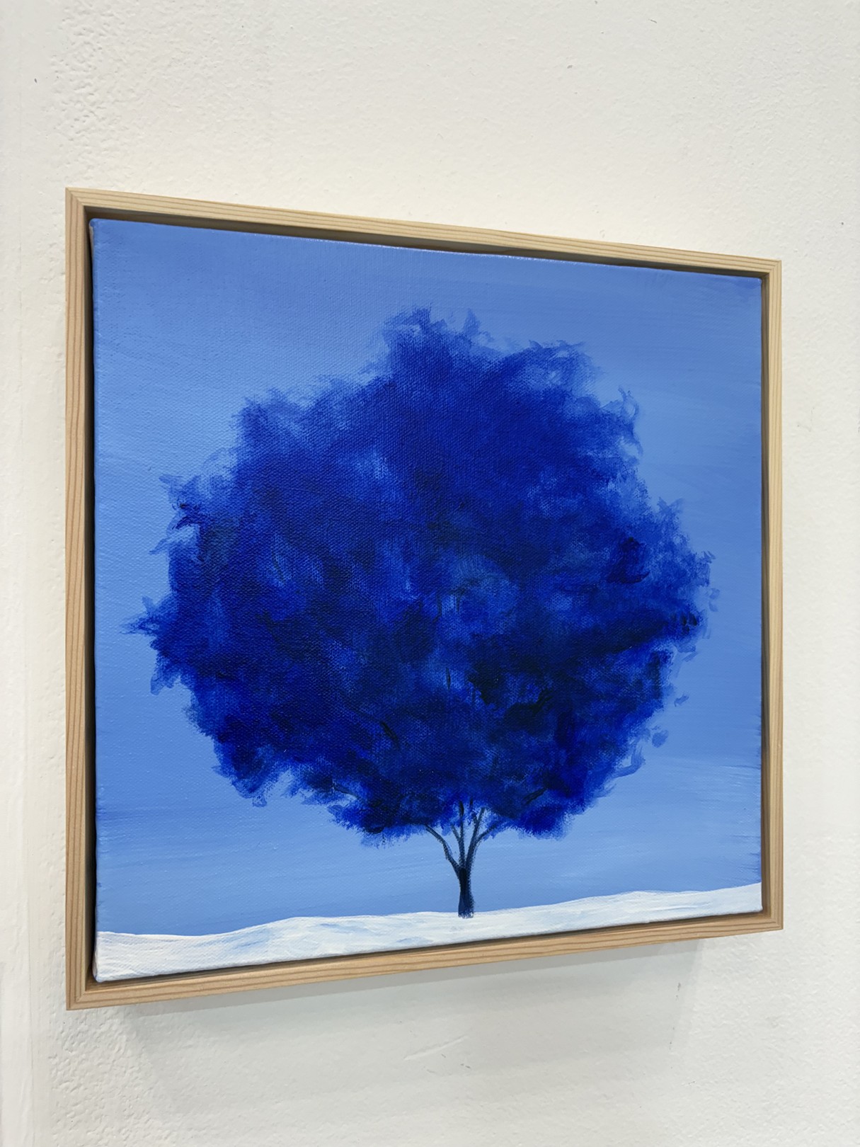 A minimalist landscape painting featuring a dark tree against a blue sky.