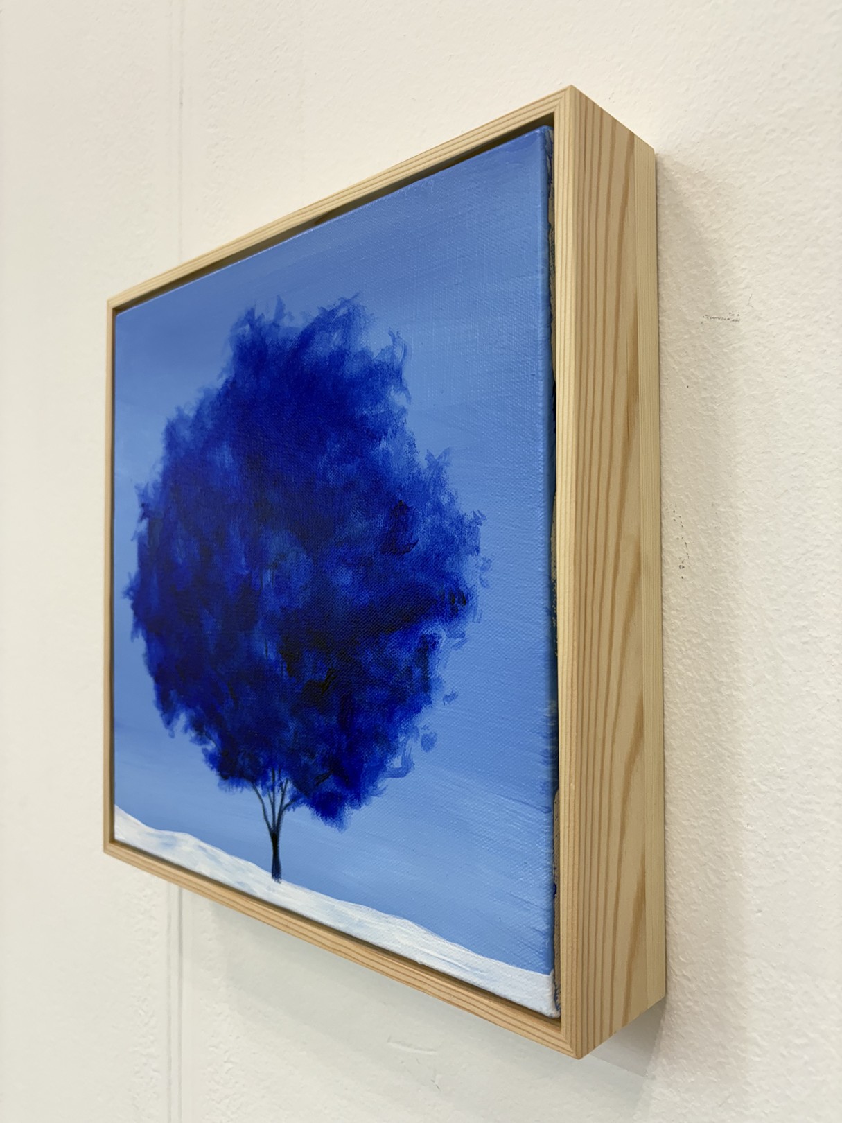 A minimalist landscape painting featuring a dark tree against a blue sky.