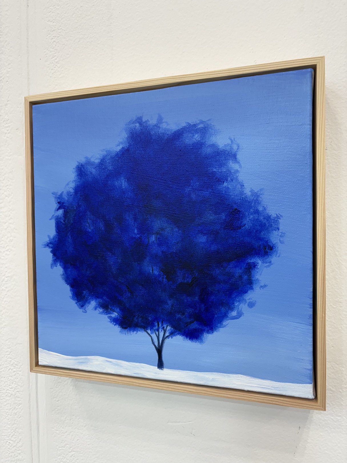A minimalist landscape painting featuring a dark tree against a blue sky.