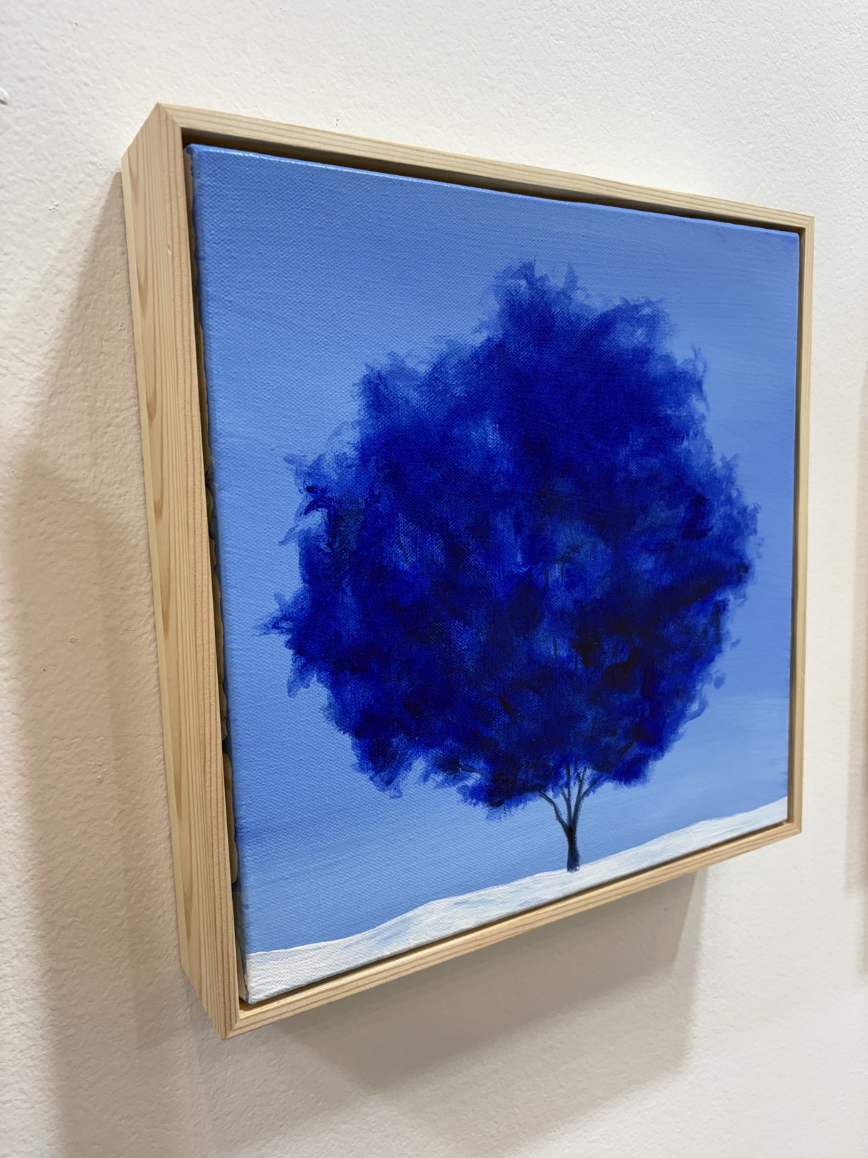 A minimalist landscape painting featuring a dark tree against a blue sky.