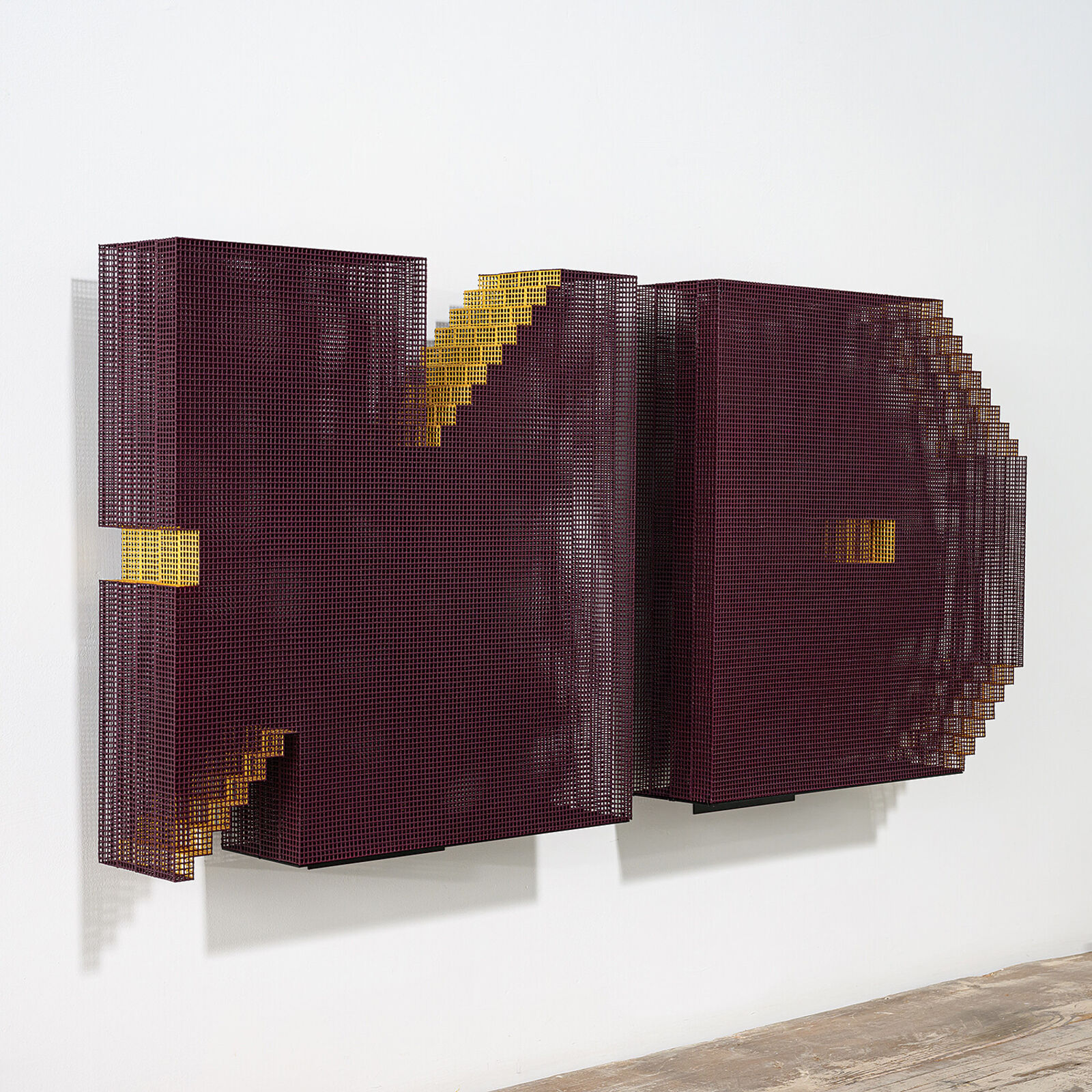 A minimalist installation featuring two pixelated, maroon-colored panels mounted on a white wall above a weathered wooden shelf.