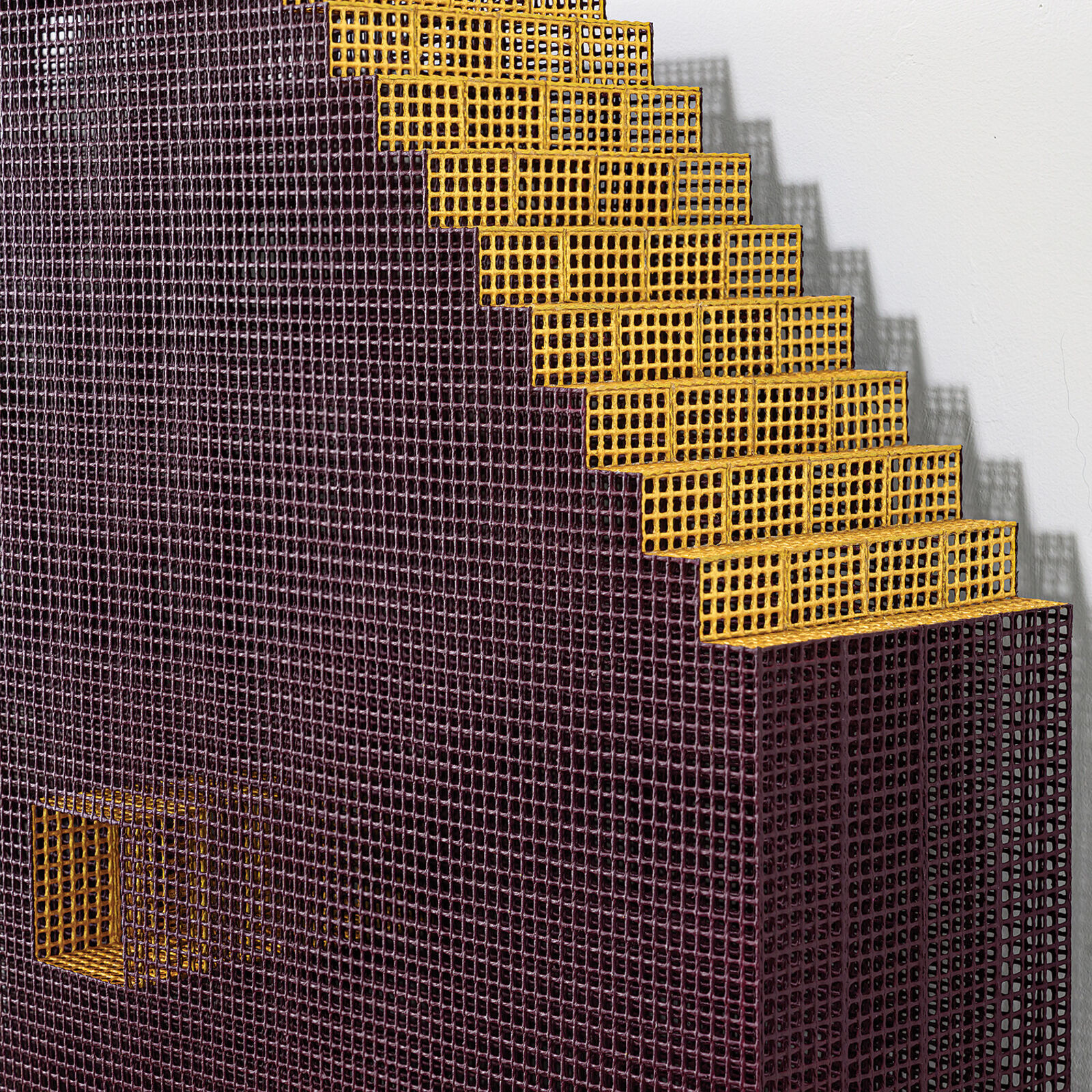 A minimalist installation featuring two pixelated, maroon-colored panels mounted on a white wall above a weathered wooden shelf.