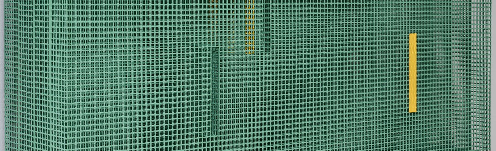 A green mesh sculpture with yellow and black geometric accents mounted on a white wall.