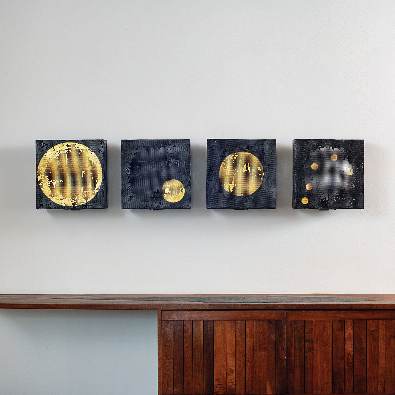 A set of four square canvases featuring pixelated celestial bodies against a minimalist interior.