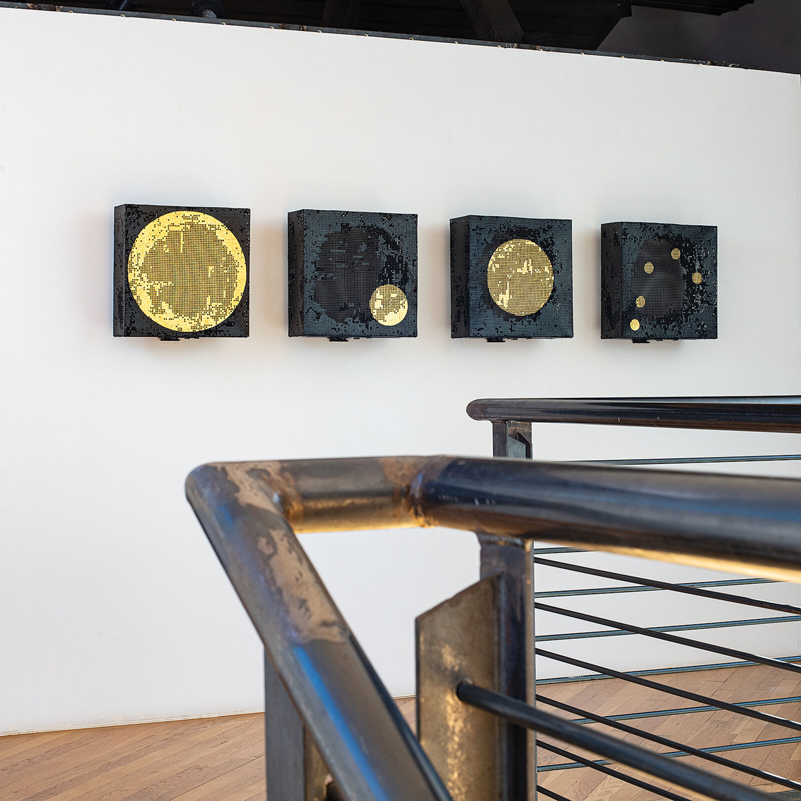 A set of four square canvases featuring pixelated celestial bodies against a minimalist interior.