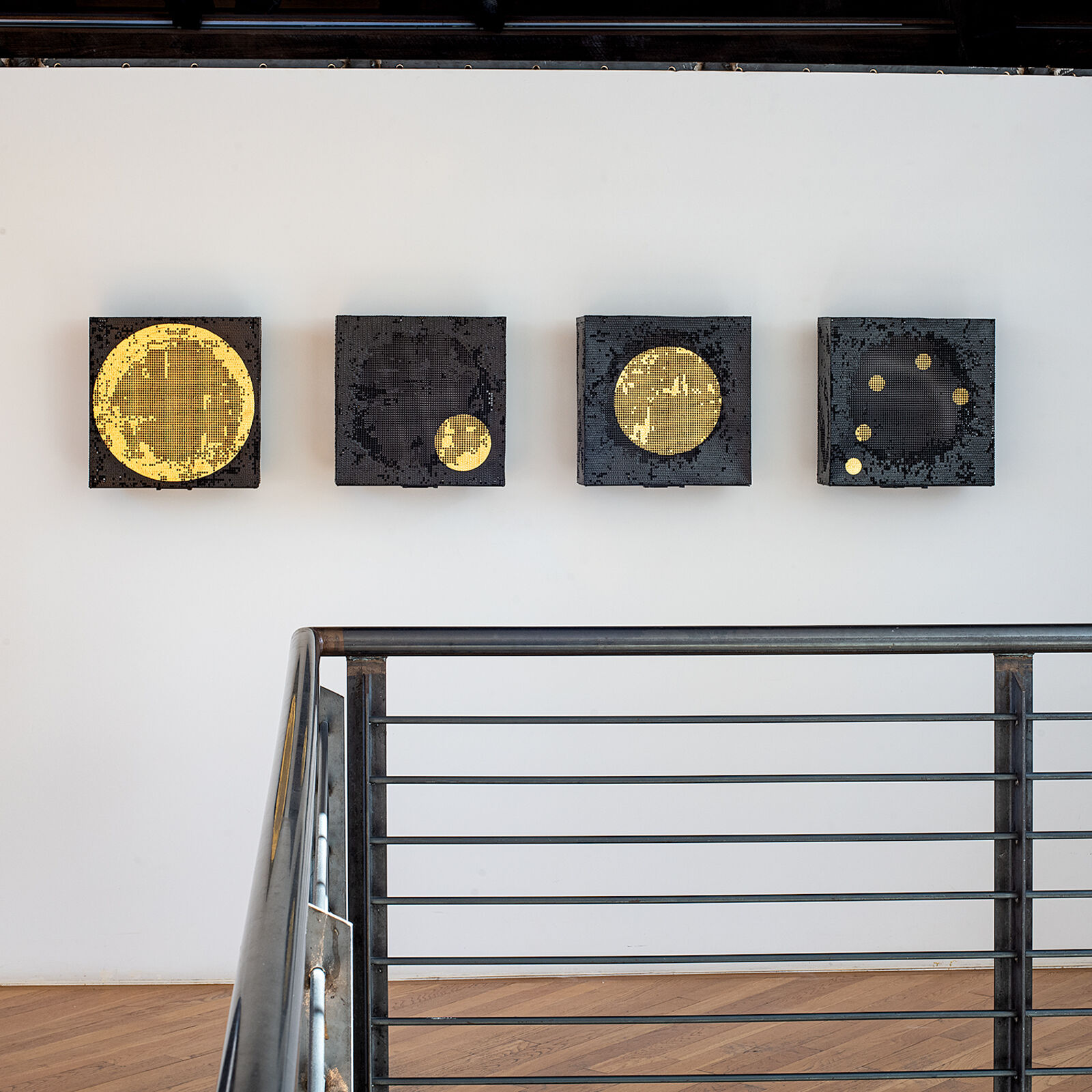 A set of four square canvases featuring pixelated celestial bodies against a minimalist interior.