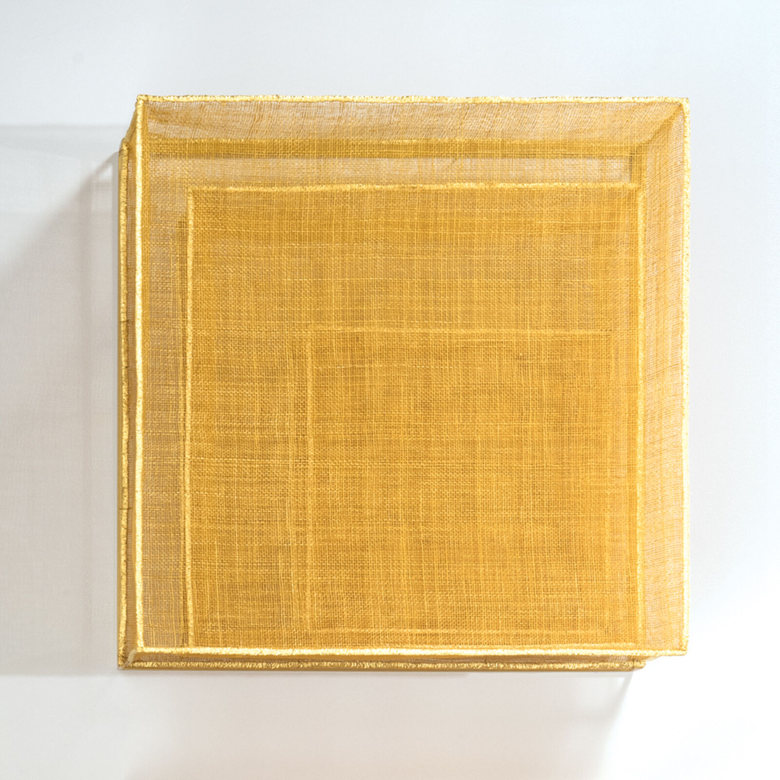 A minimalist textile artwork featuring a golden-yellow woven square with layered geometric forms.