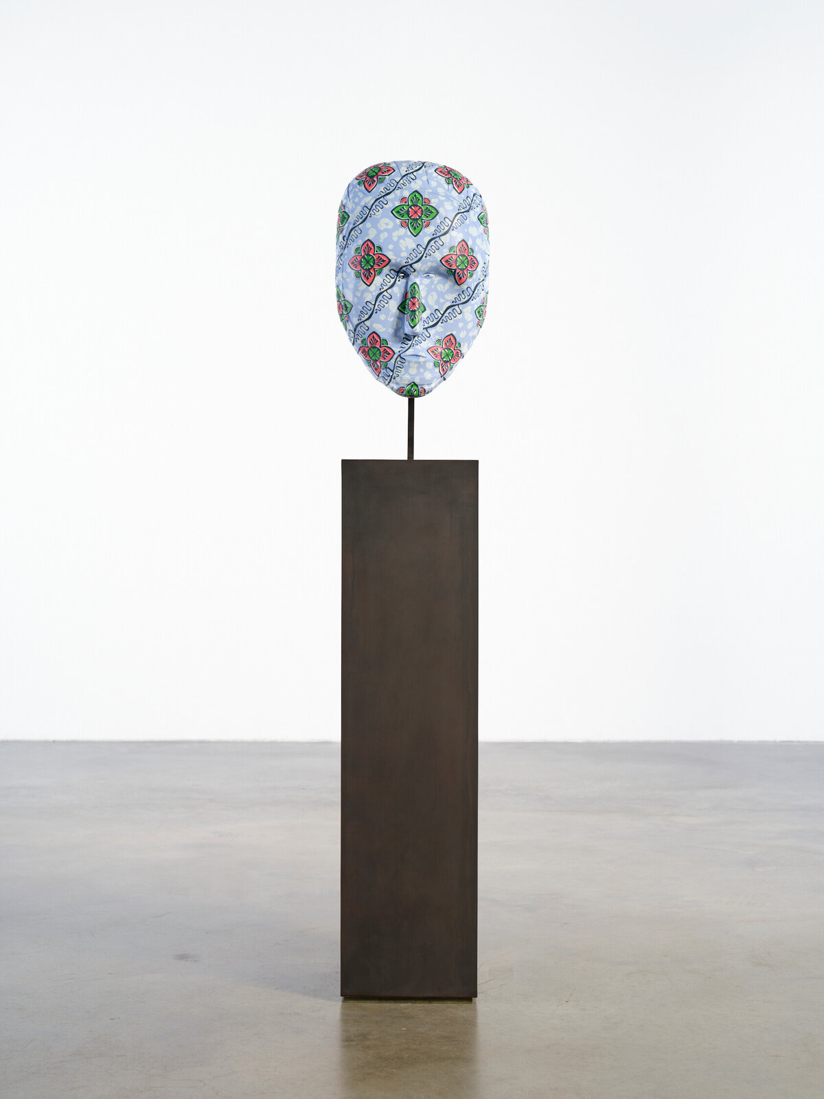 A tall, dark pedestal supports a slender rod topped with a patterned, balloon-like object.