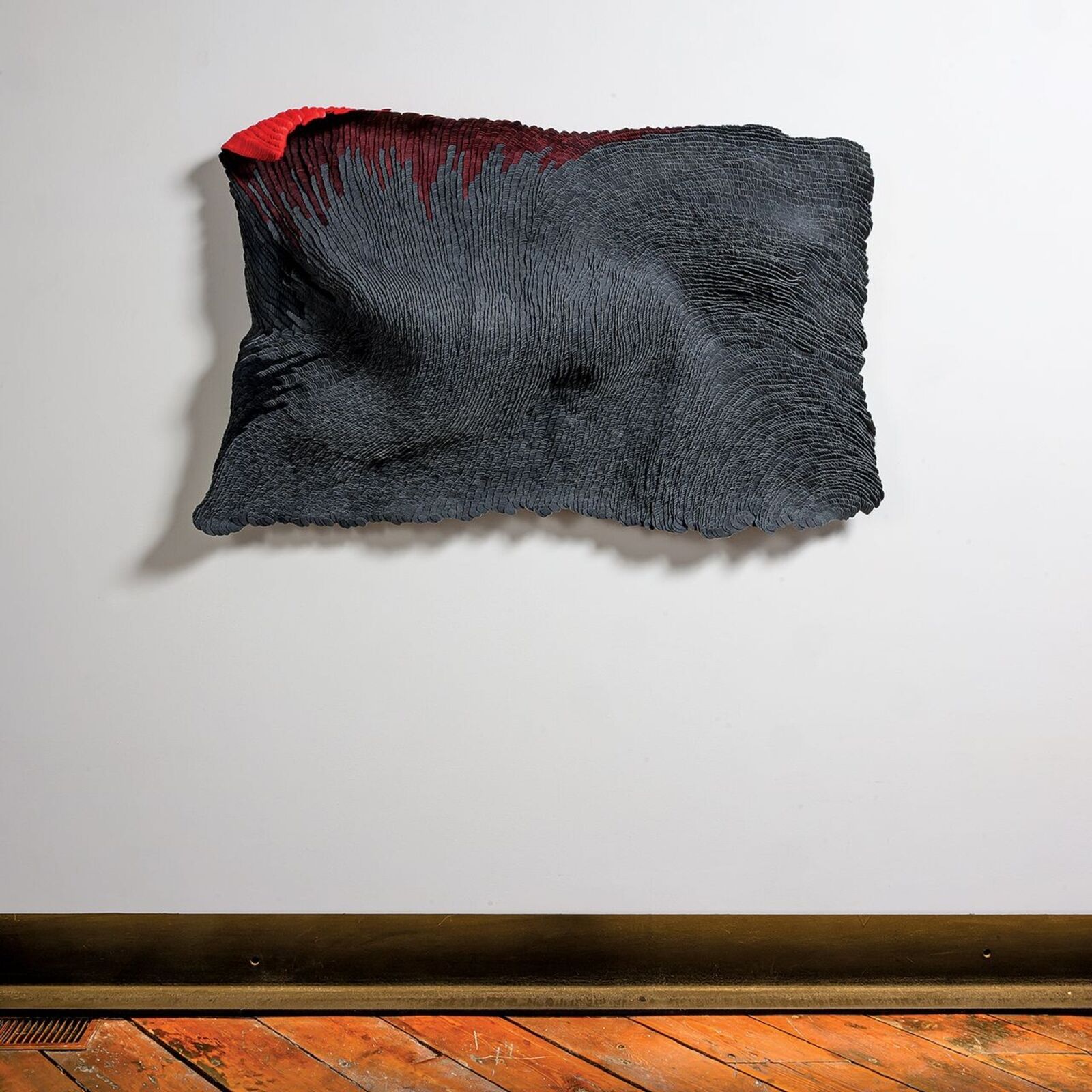 A black and red piece of art hanging on a wall.