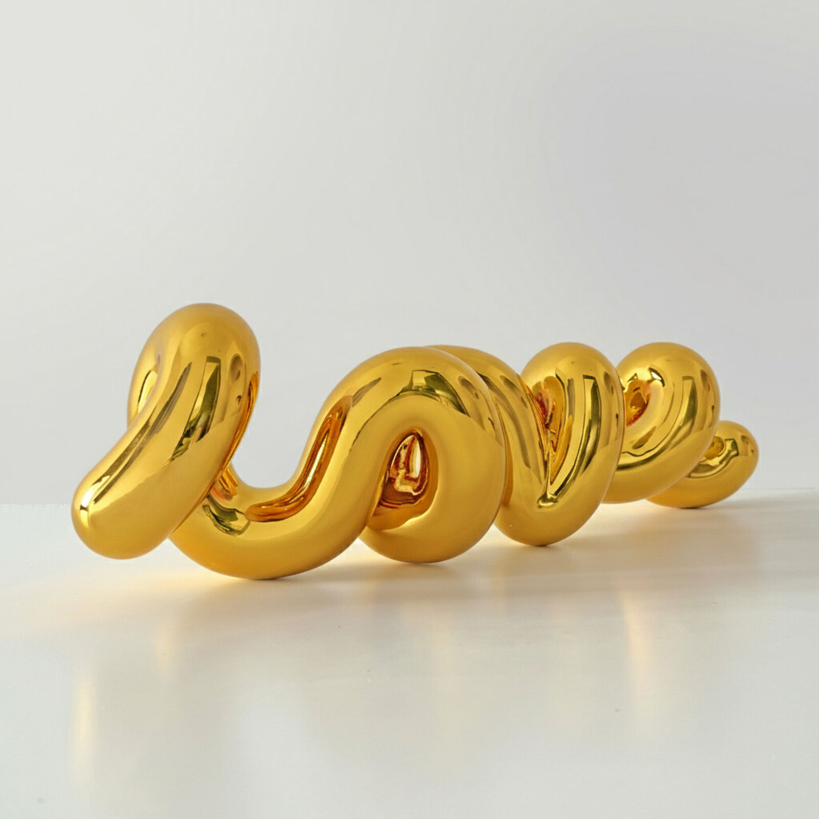A gold sculpture of a spiral design on a white surface.