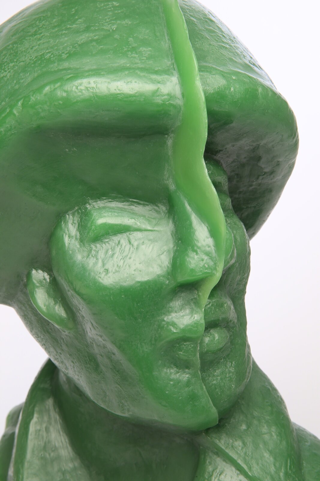 A glossy green bust sculpture displayed on a black metal stand.