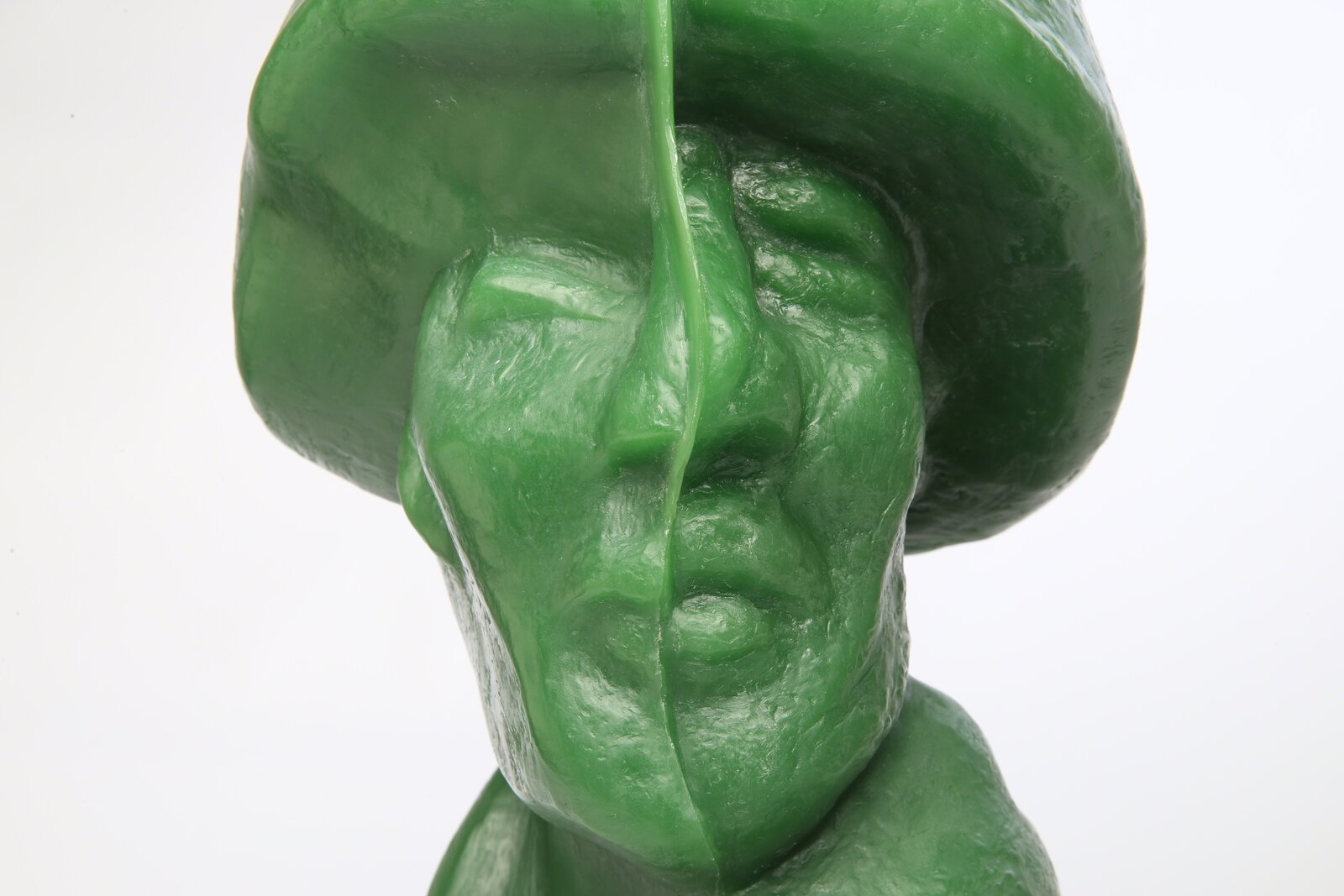 A glossy green bust sculpture displayed on a black metal stand.