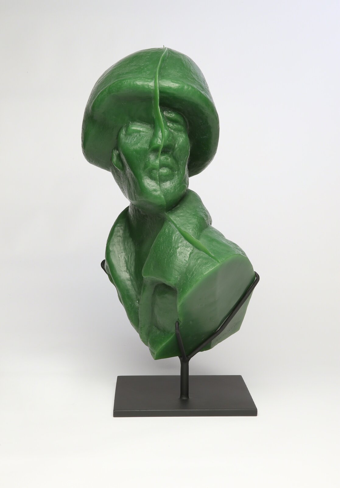A glossy green bust sculpture displayed on a black metal stand.