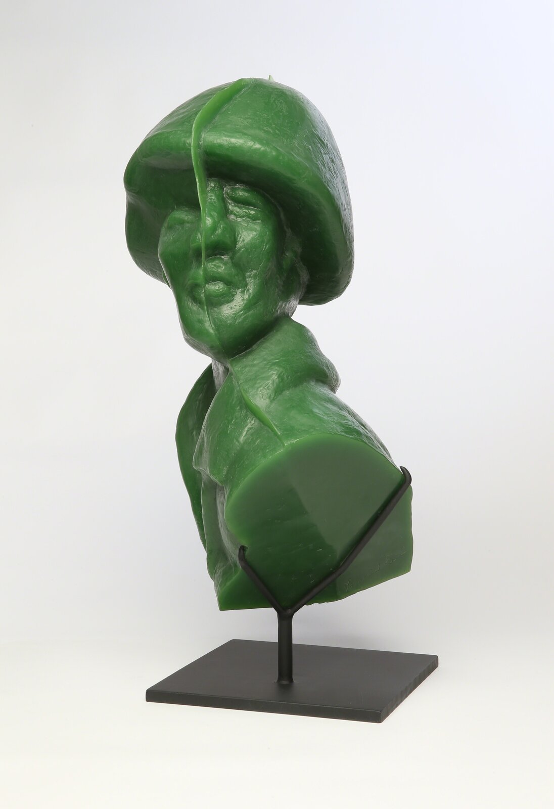 A glossy green bust sculpture displayed on a black metal stand.