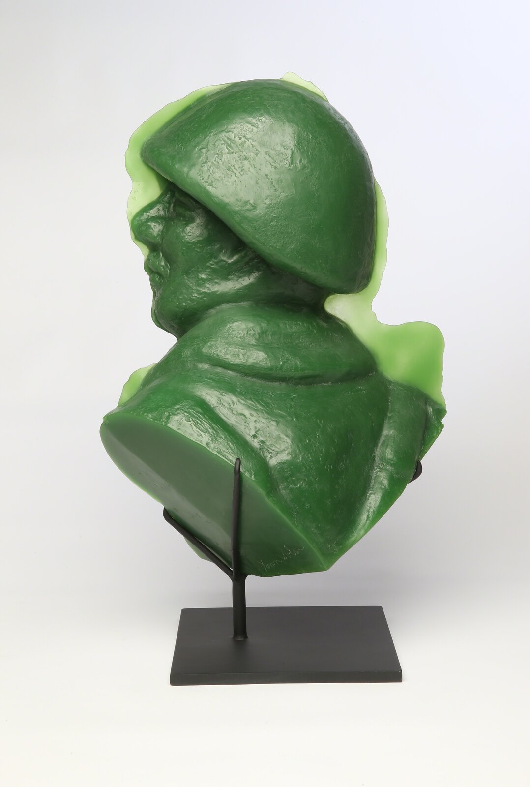 A glossy green bust sculpture displayed on a black metal stand.