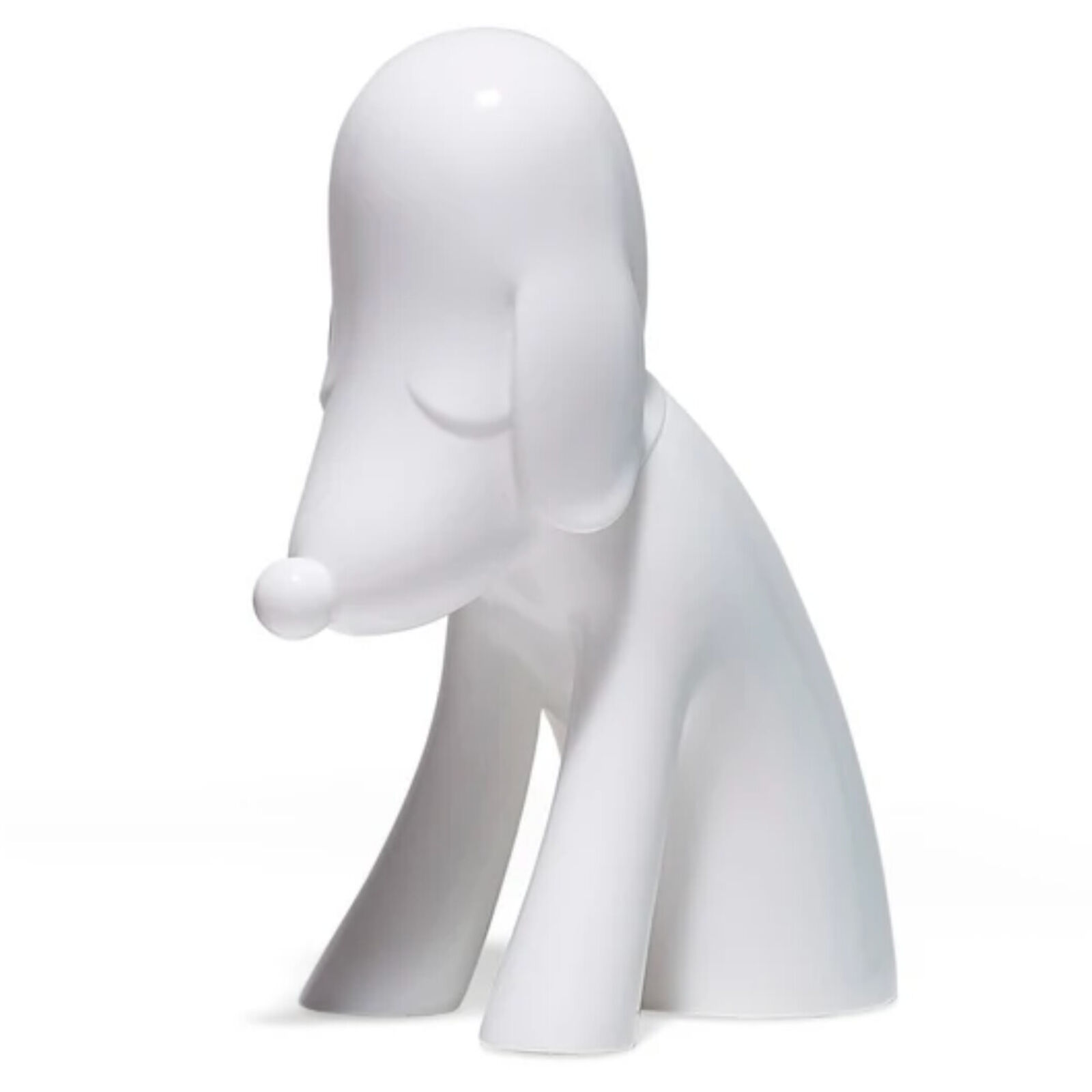 A white dog figurine sitting on a white surface.