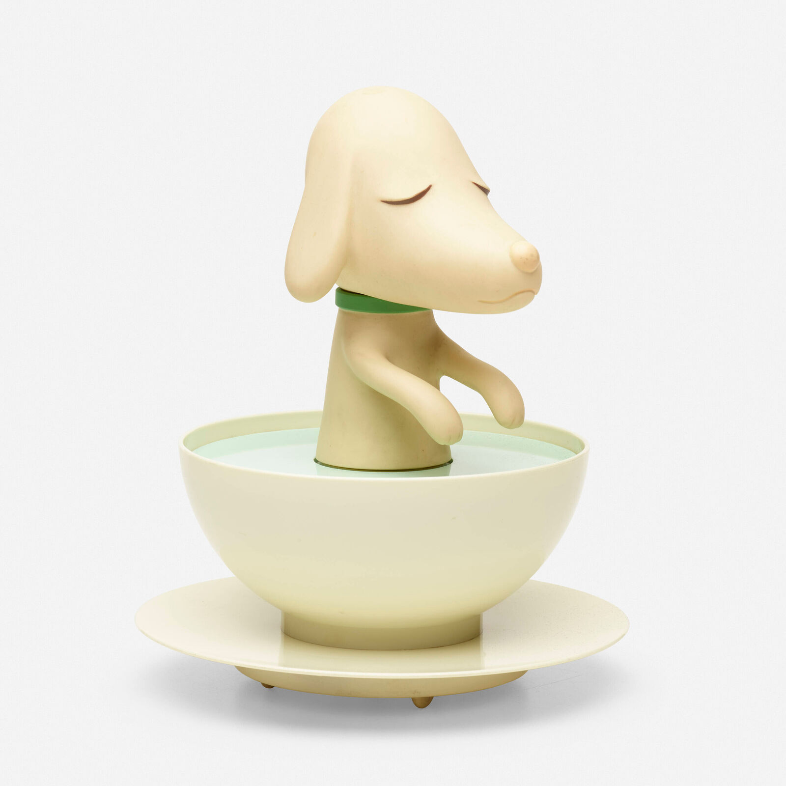 A small figurine of a dog sitting in a bowl of water.