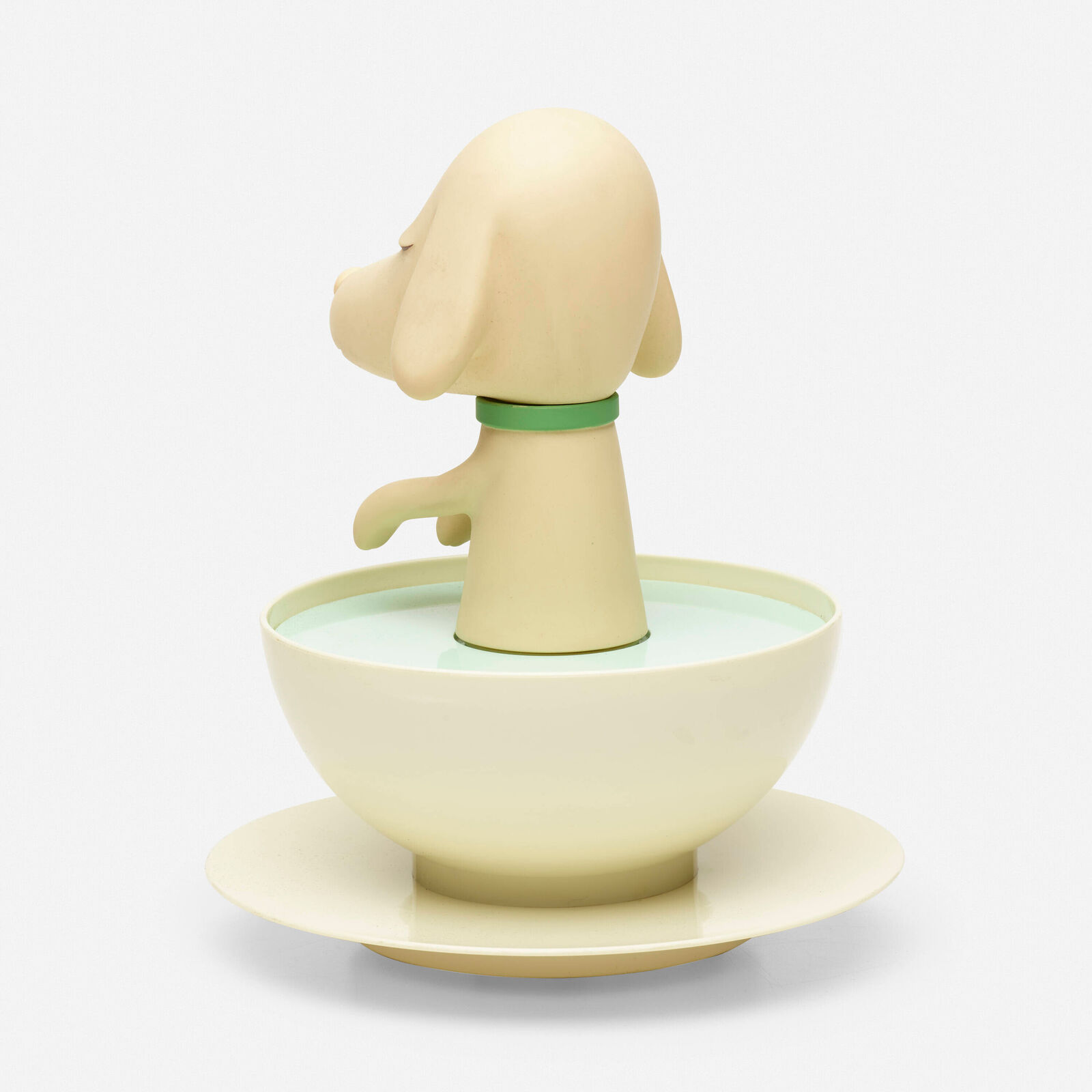 A small figurine of a dog sitting in a bowl of water.