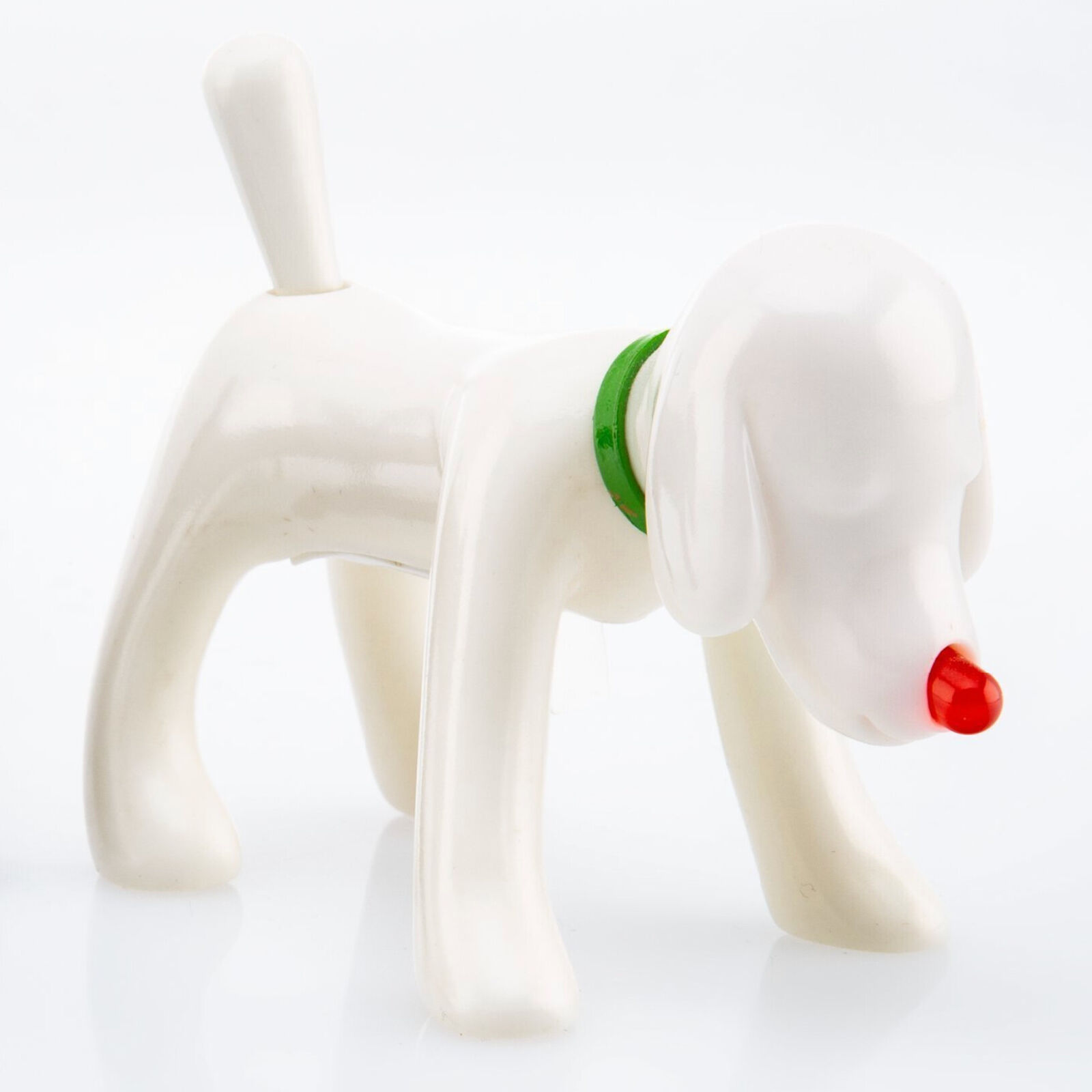 A white dog figurine with a green collar and a red nose.