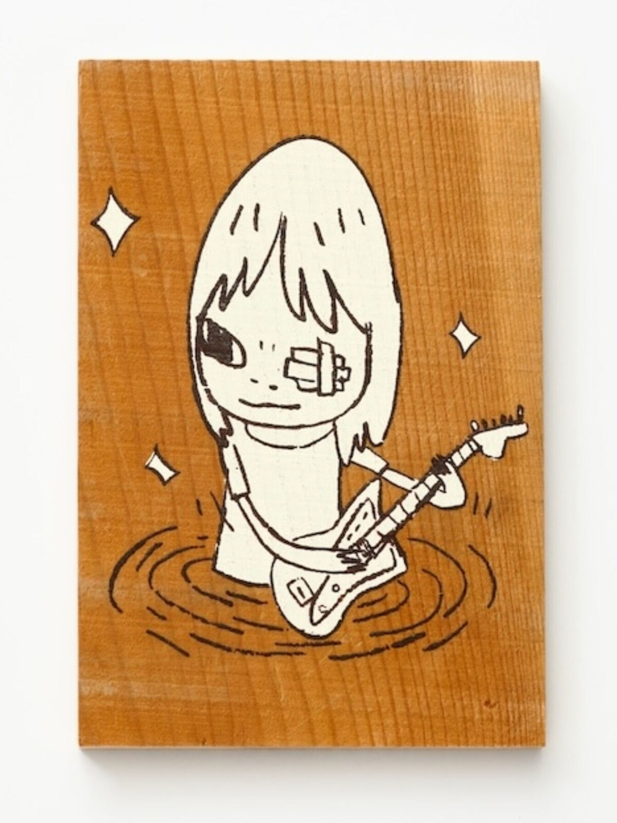 A wooden stamp with a drawing of a girl playing a guitar.