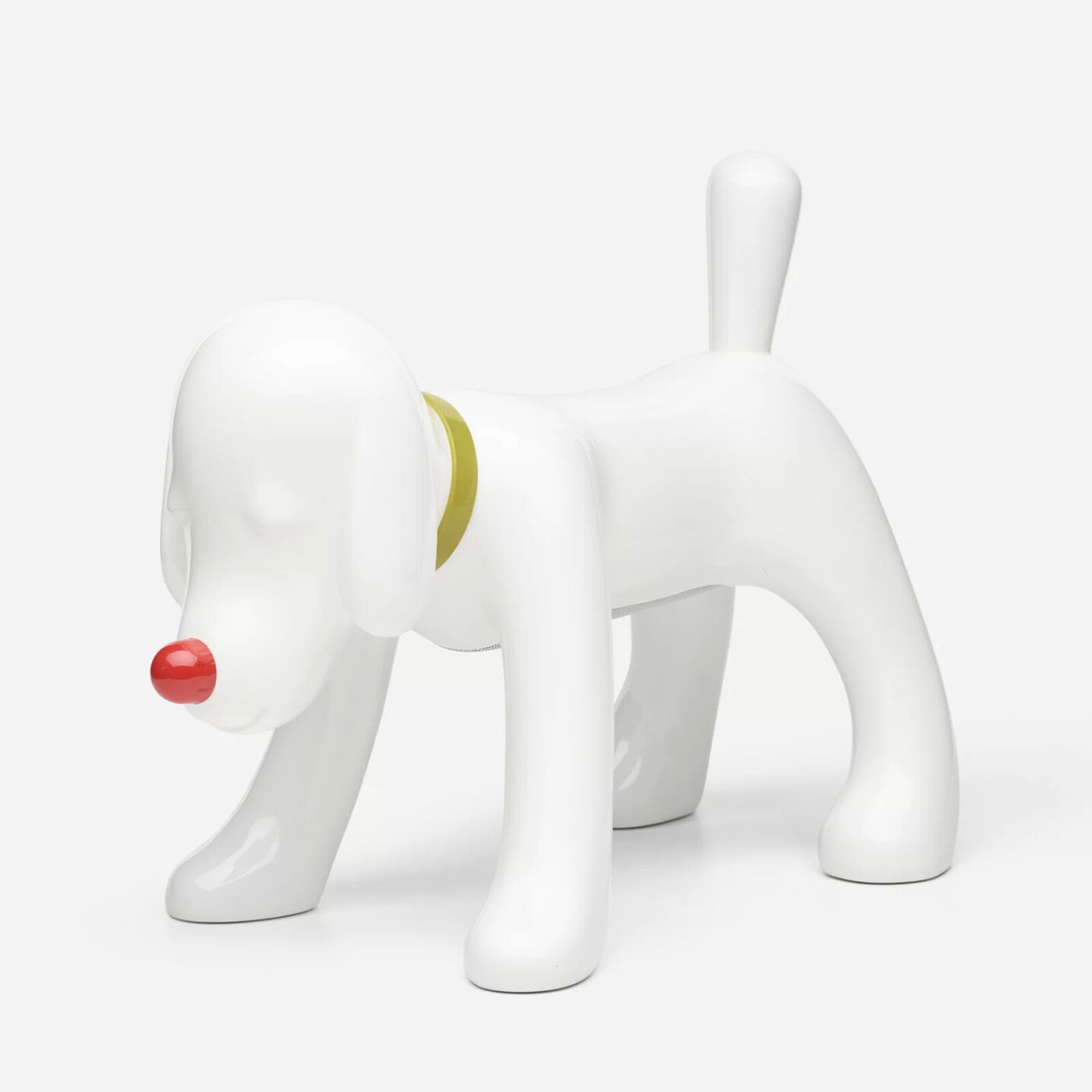 A white dog figurine with a red nose and a yellow collar.