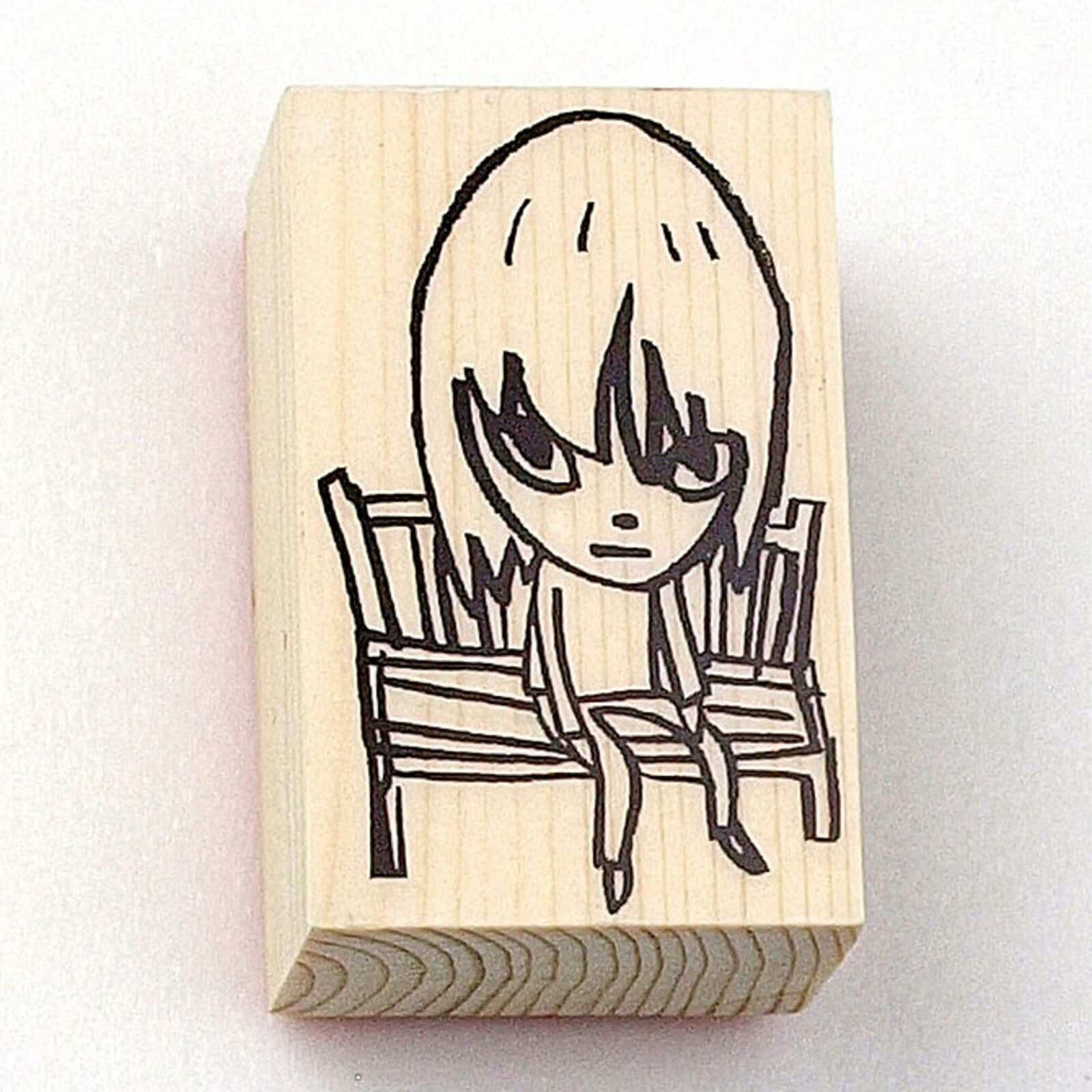 A rubber stamp with a drawing of a girl sitting on a chair.