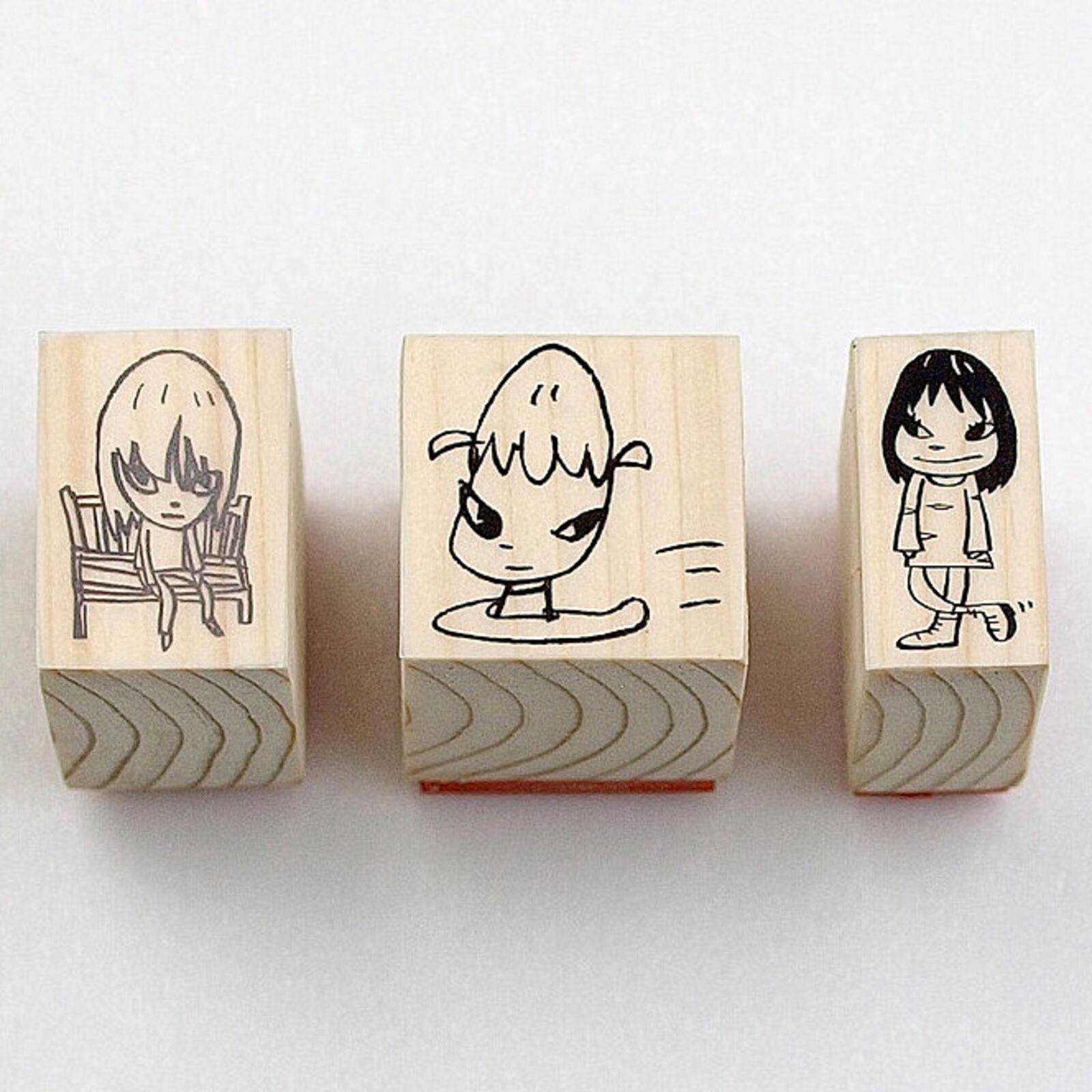 A set of three wooden blocks with a drawing of a girl sitting on a chair.