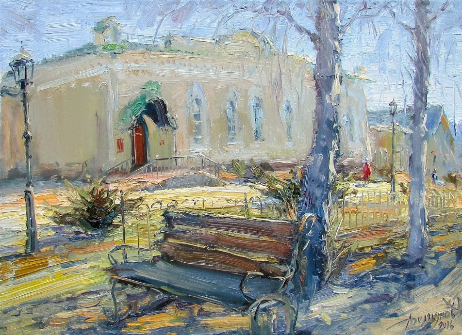 A sun-drenched street scene featuring a park bench, bare trees, and a large building in the background.