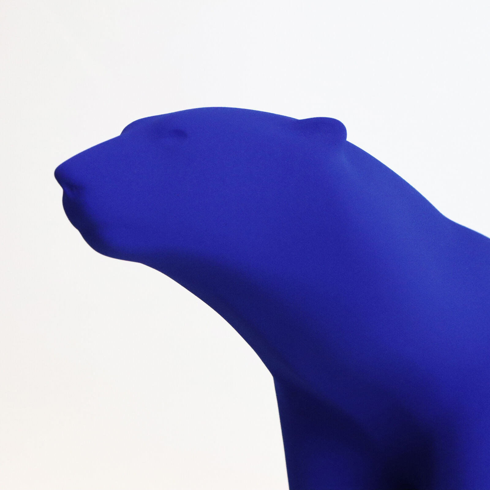 A smooth, matte blue sculpture of a four-legged animal in a walking pose.