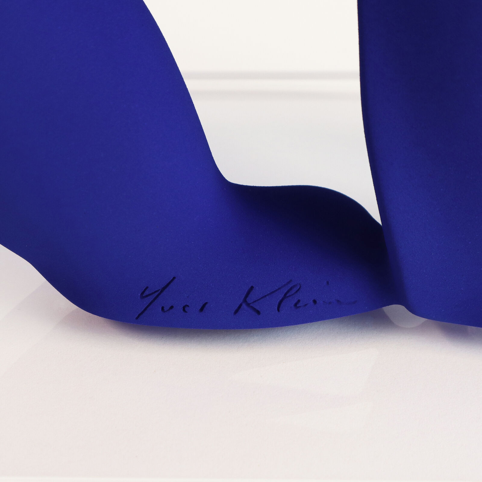 A smooth, matte blue sculpture of a four-legged animal in a walking pose.