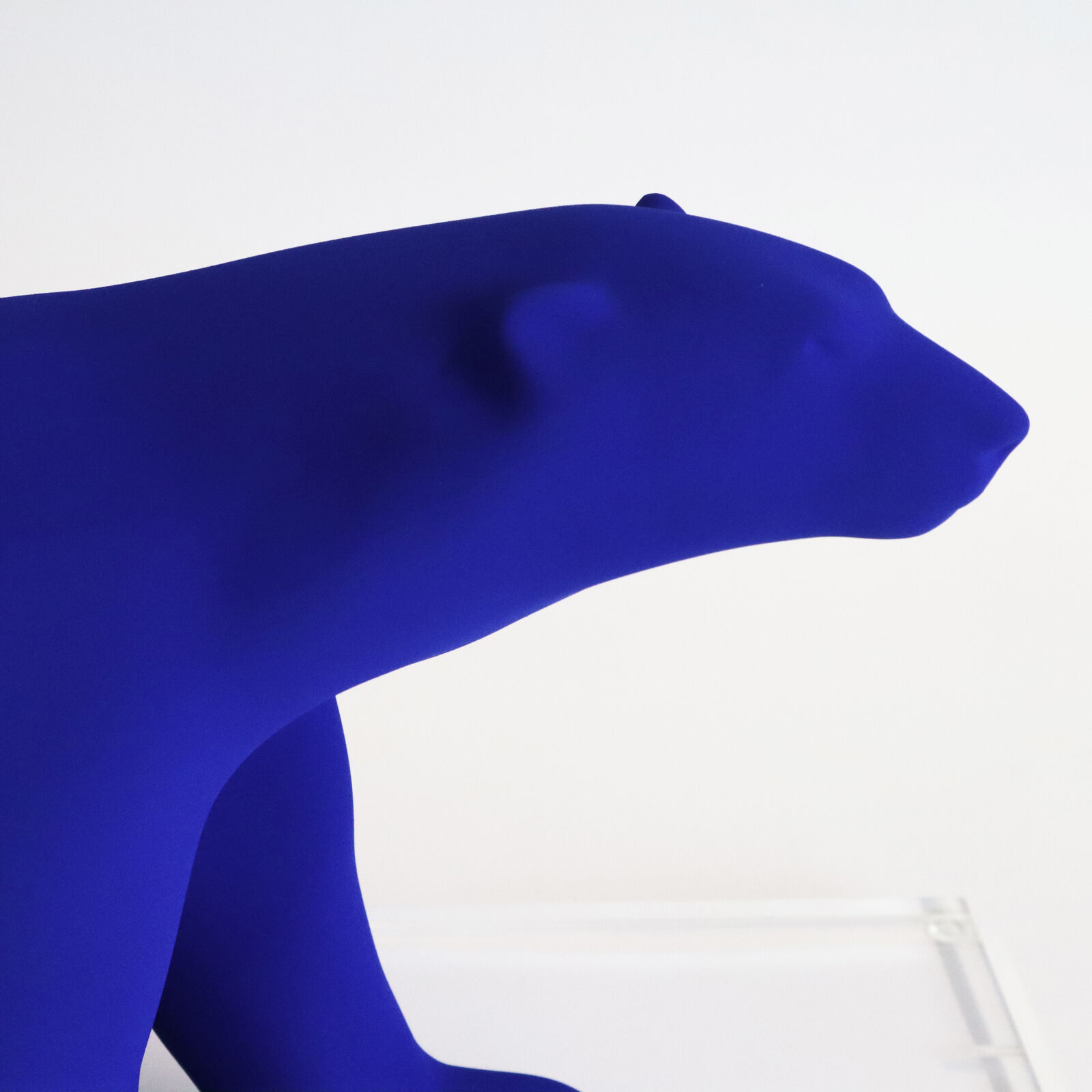 A smooth, matte blue sculpture of a four-legged animal in a walking pose.