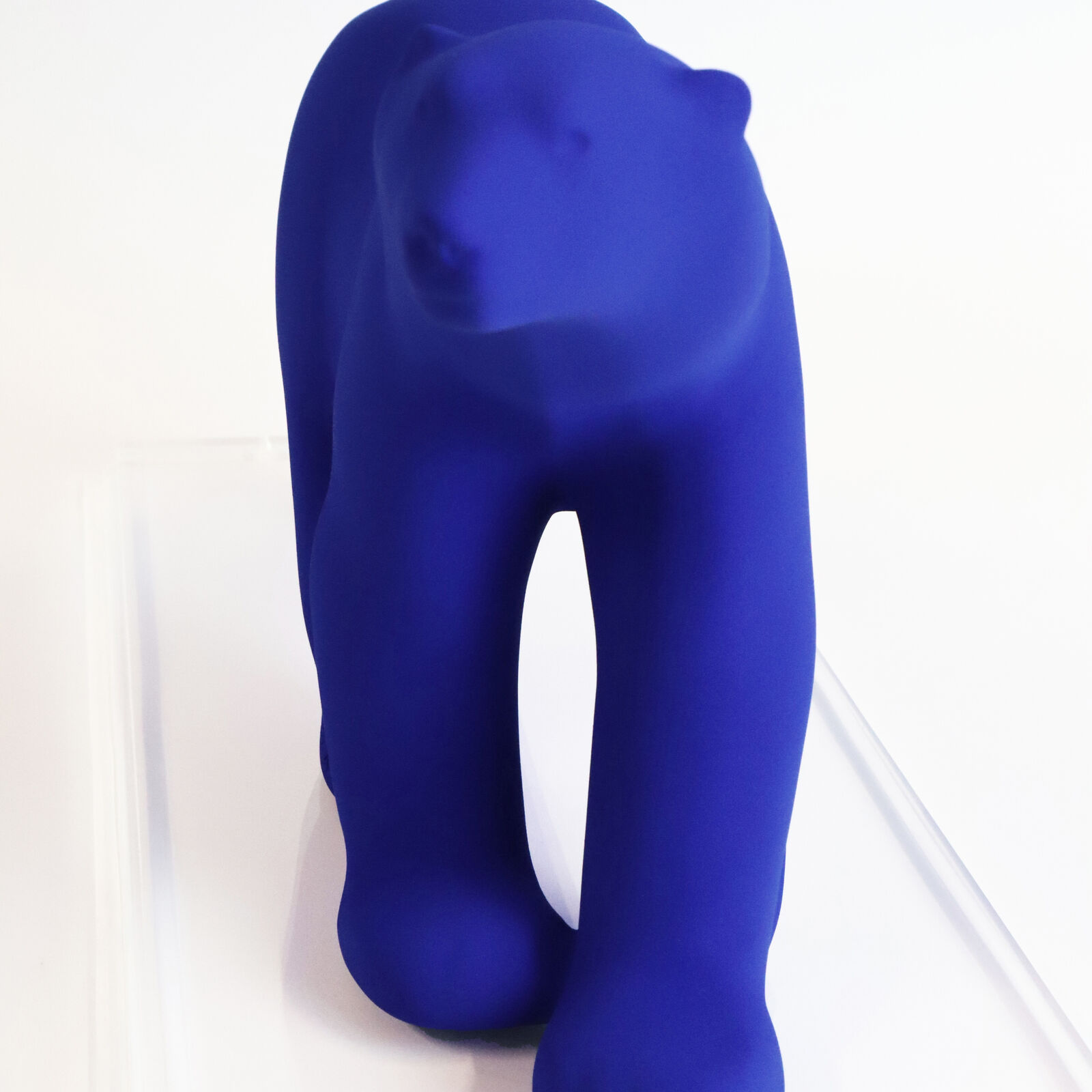 A smooth, matte blue sculpture of a four-legged animal in a walking pose.